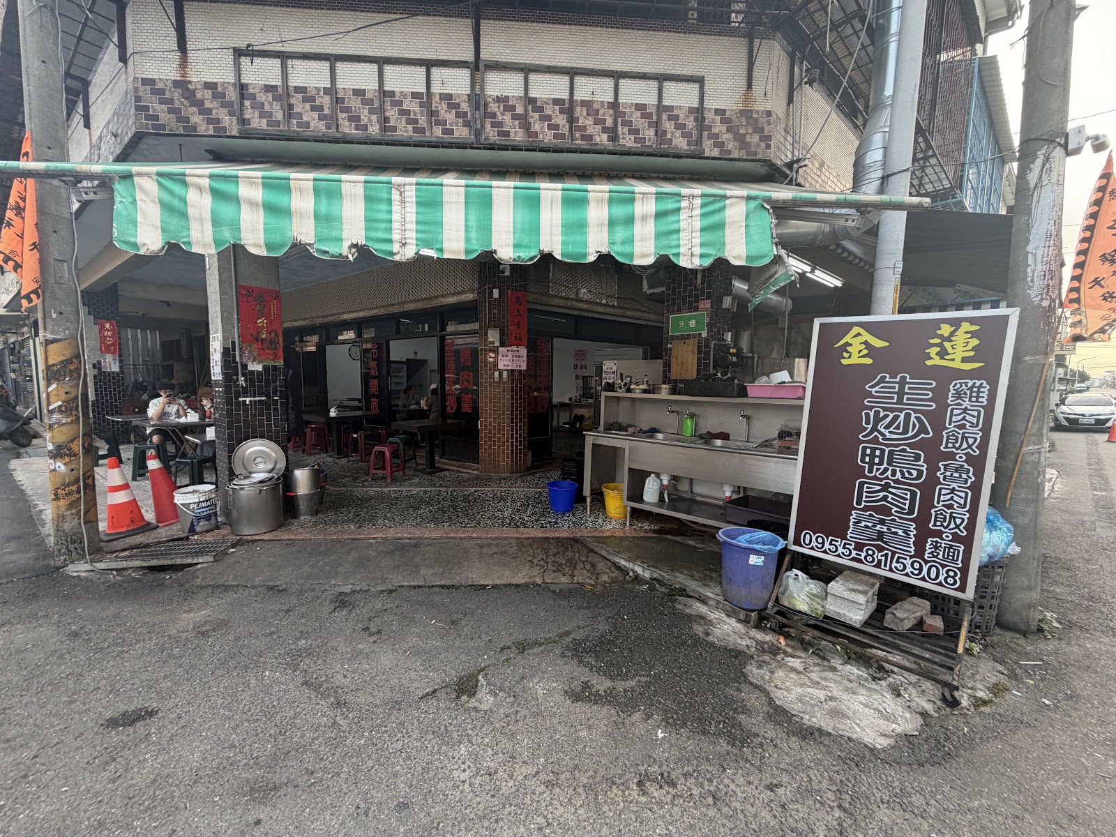 金蓮生炒鴨肉羹店面招牌，綠白條紋遮陽棚下擺放用餐桌椅
