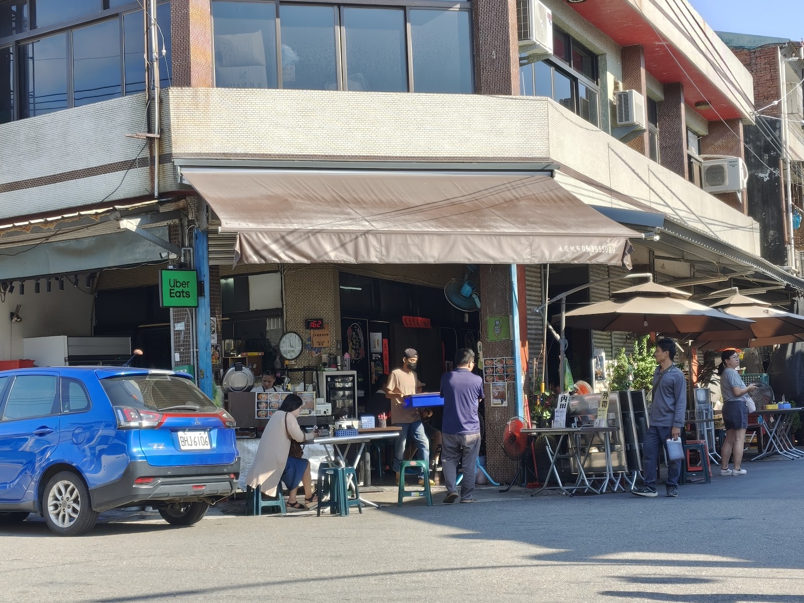 三角窗黃金魚焿店面外觀，騎樓下擺放桌椅，遮陽棚下有Uber Eats招牌