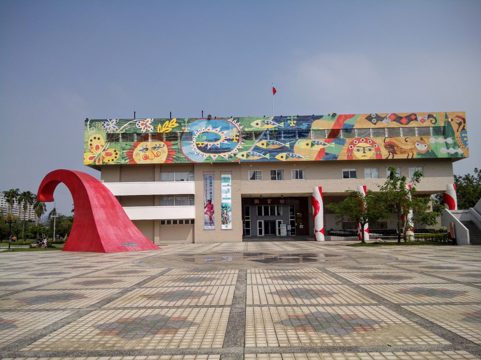 岡山文化中心外觀,白色建築搭配繽紛馬賽克壁畫與紅色弧形裝置藝術