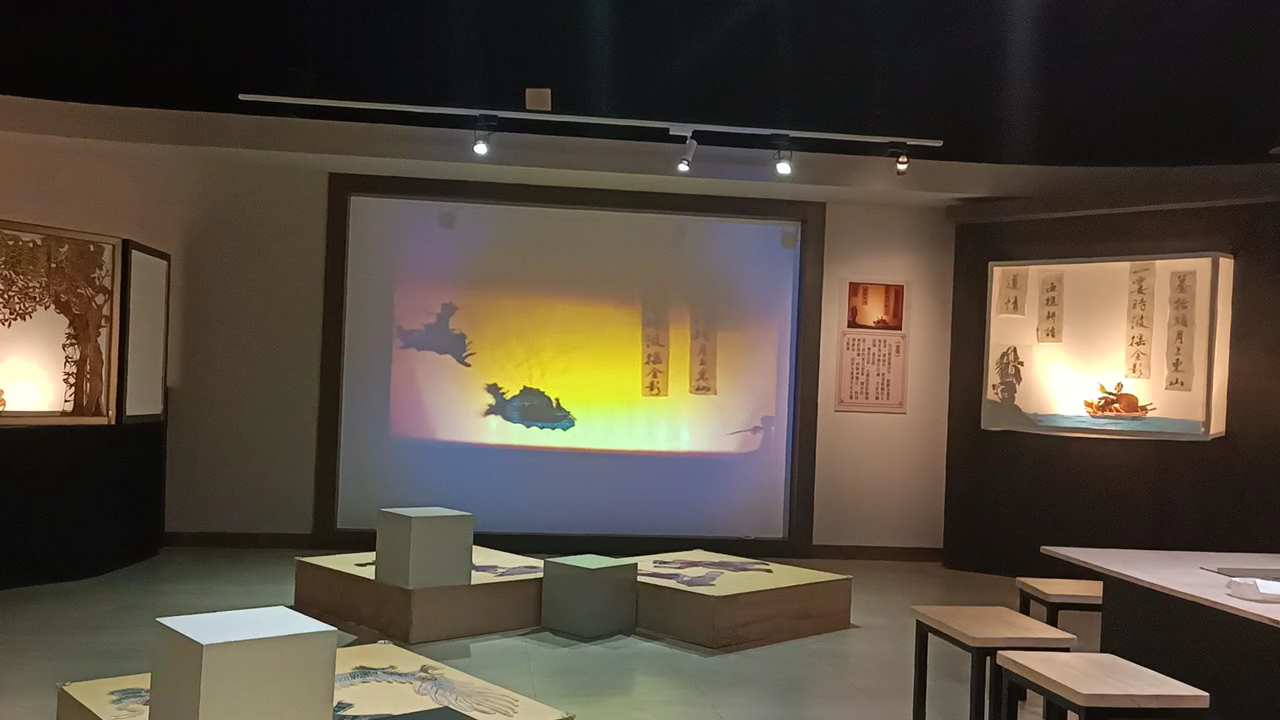 皮影戲館內展演廳,投影布幕打著皮影戲場景,燈光呈現藍紫橘色調