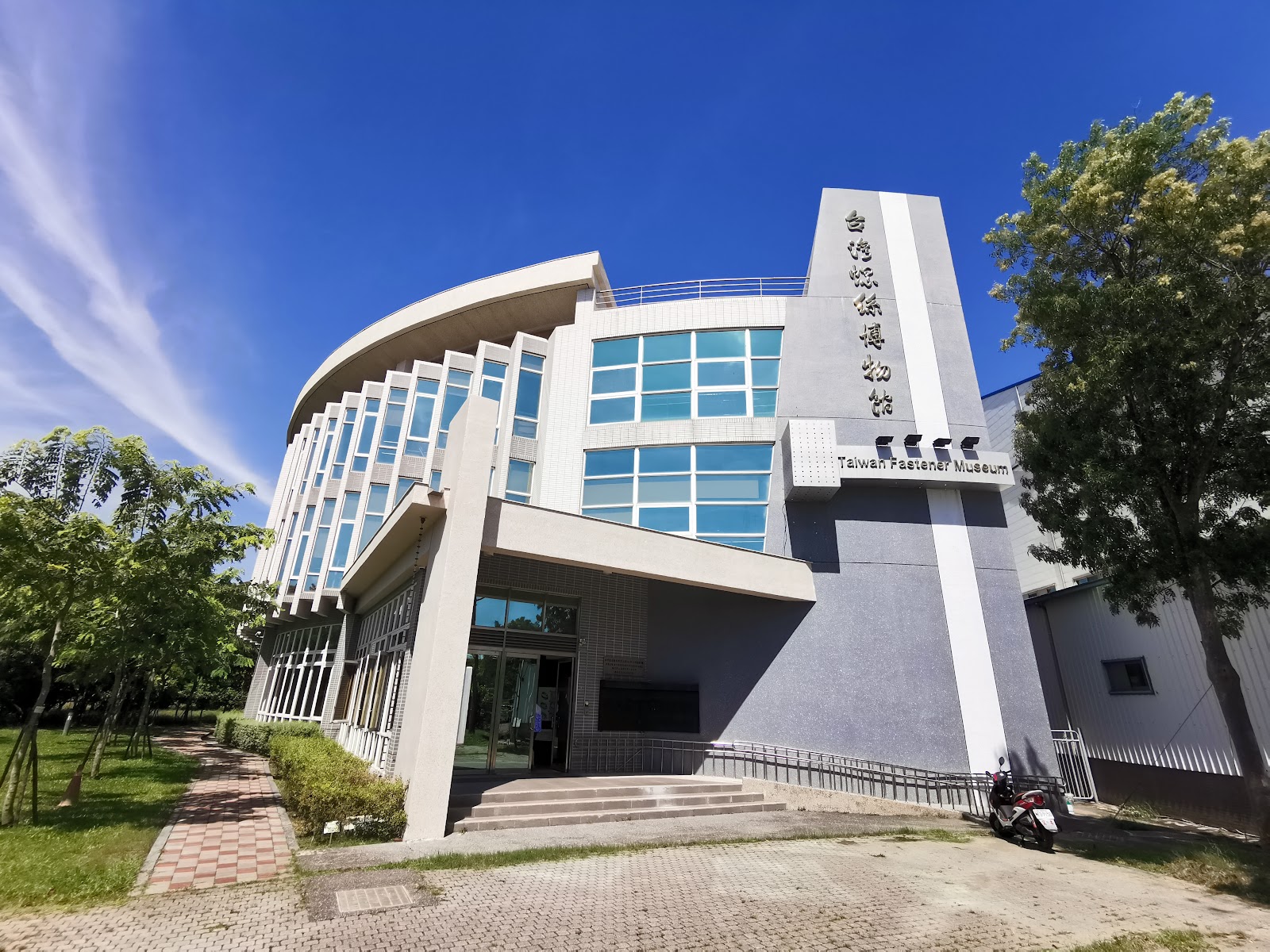 台灣螺絲博物館建築外觀,白色弧形量體搭配玻璃帷幕,藍天白雲
