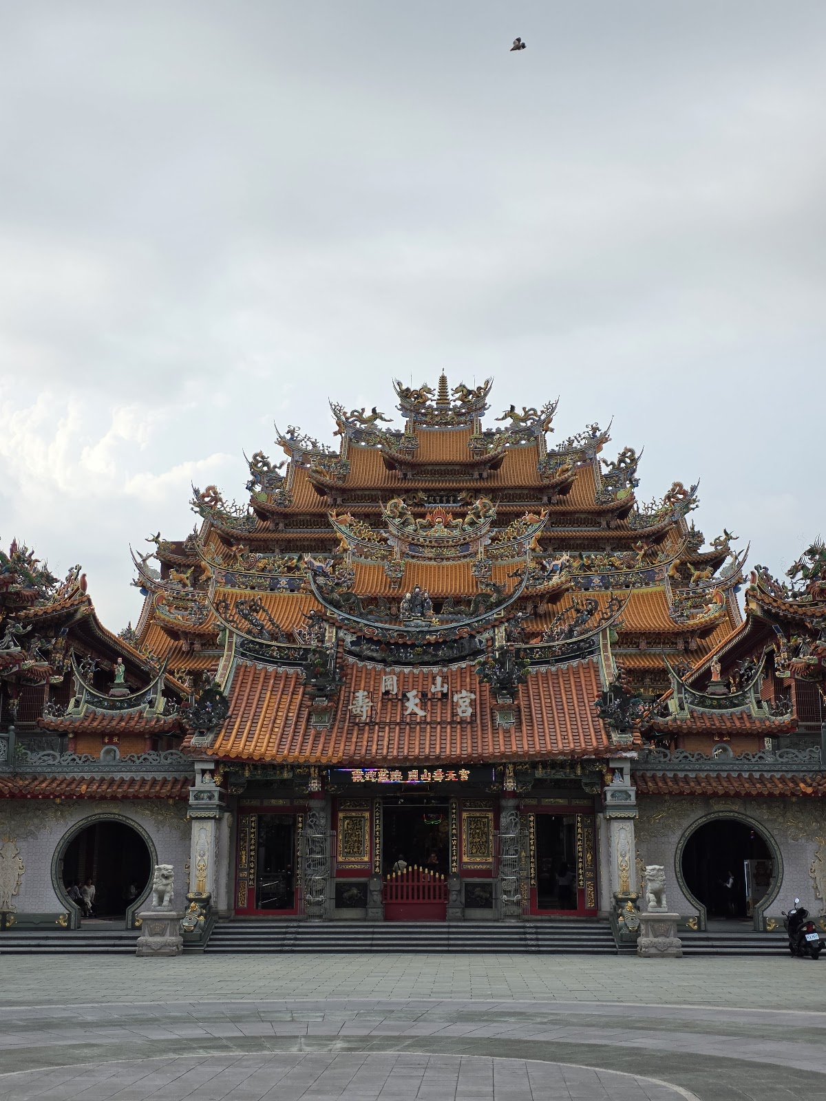 岡山壽天宮廟埕正面近景,多層次燕尾脊與剪黏裝飾,陰天氛圍