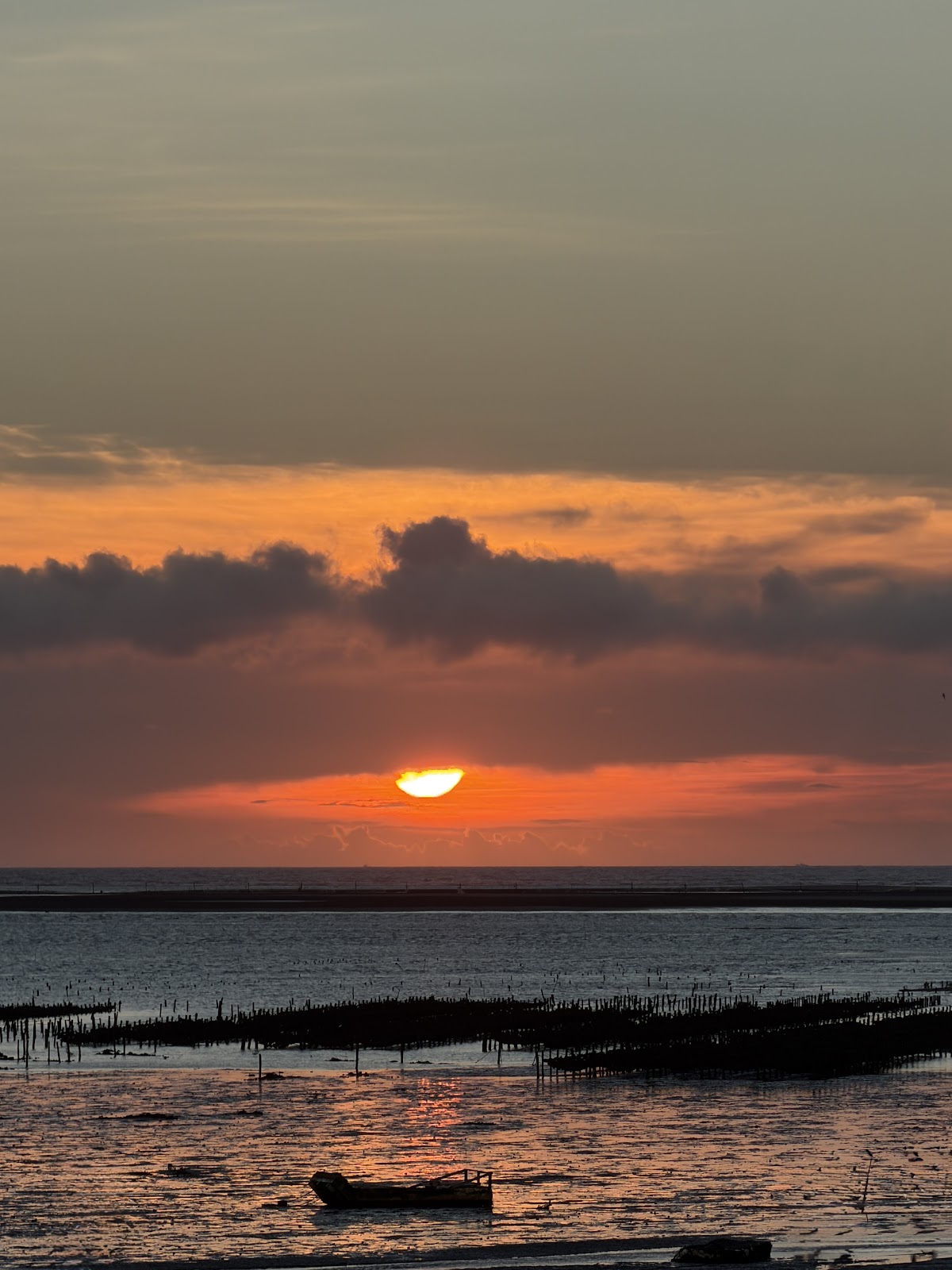 線西海邊夕陽染紅蚵架與小船剪影