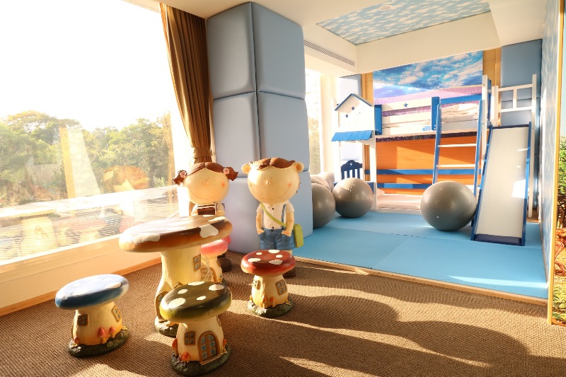 兒童遊戲室，內有造型蘑菇桌椅、卡通人偶裝飾、溜滑梯和大型健身球