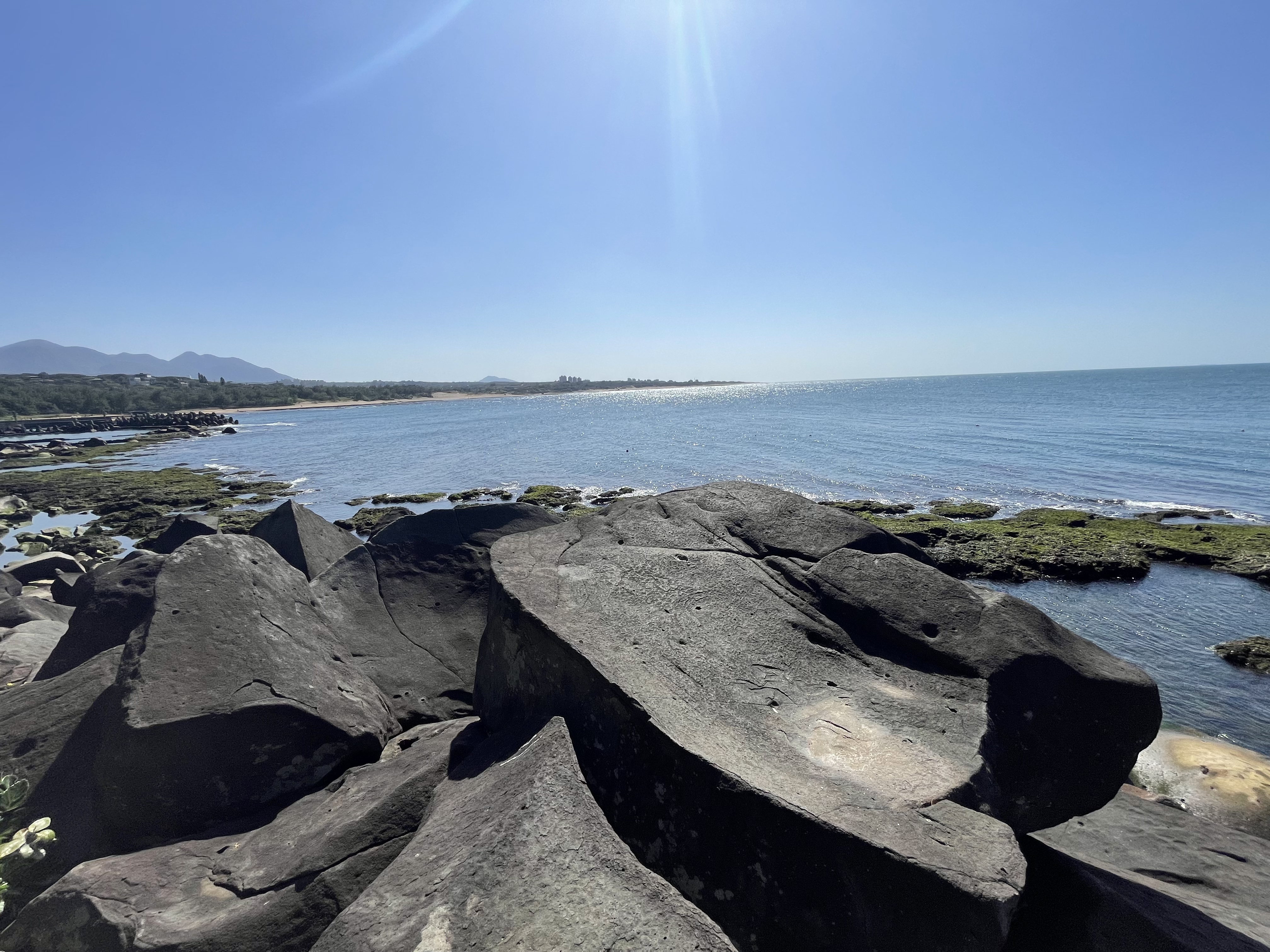 前景黑色岩石、後方藍色大海與晴朗天空的海岸風景