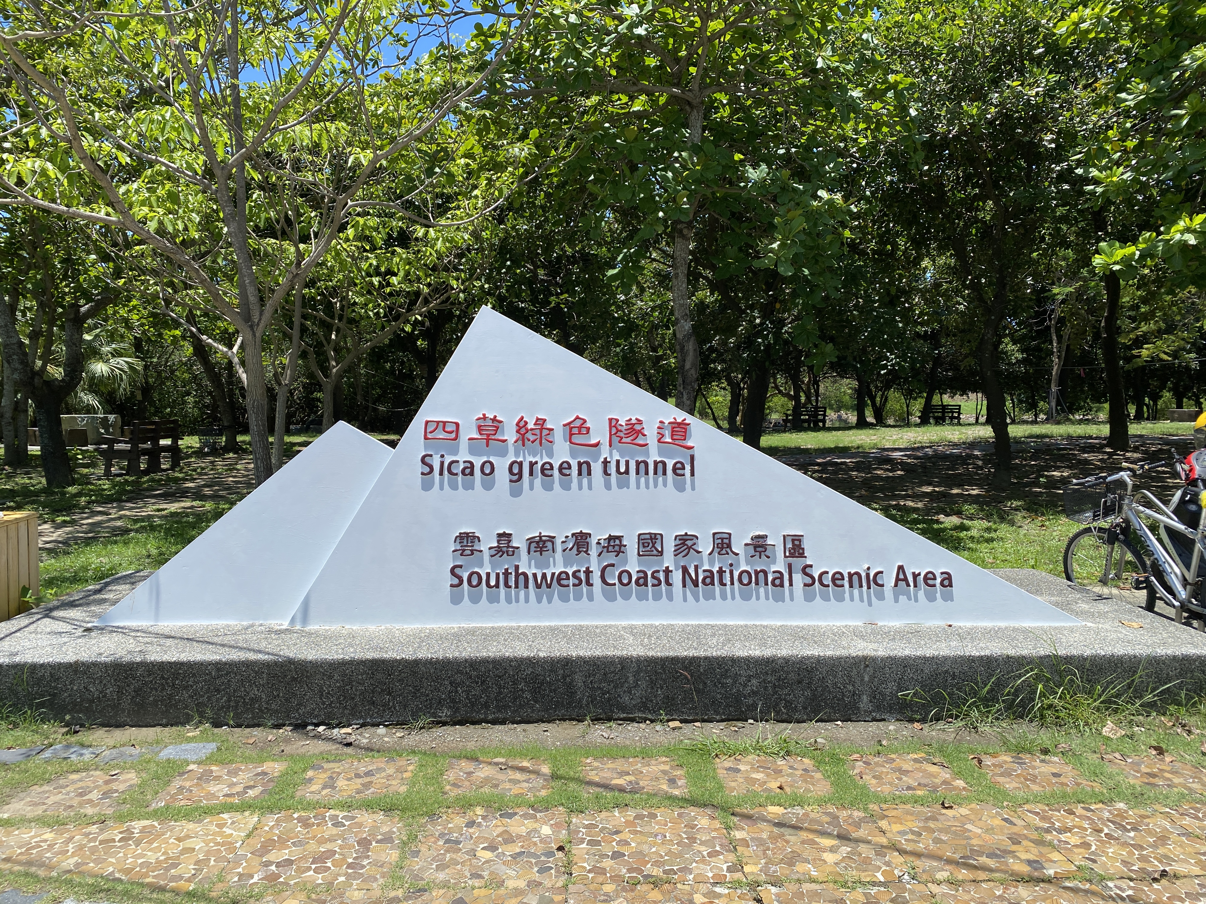 寫有四草綠色隧道與雲嘉南濱海國家風景區的白色地標石牌