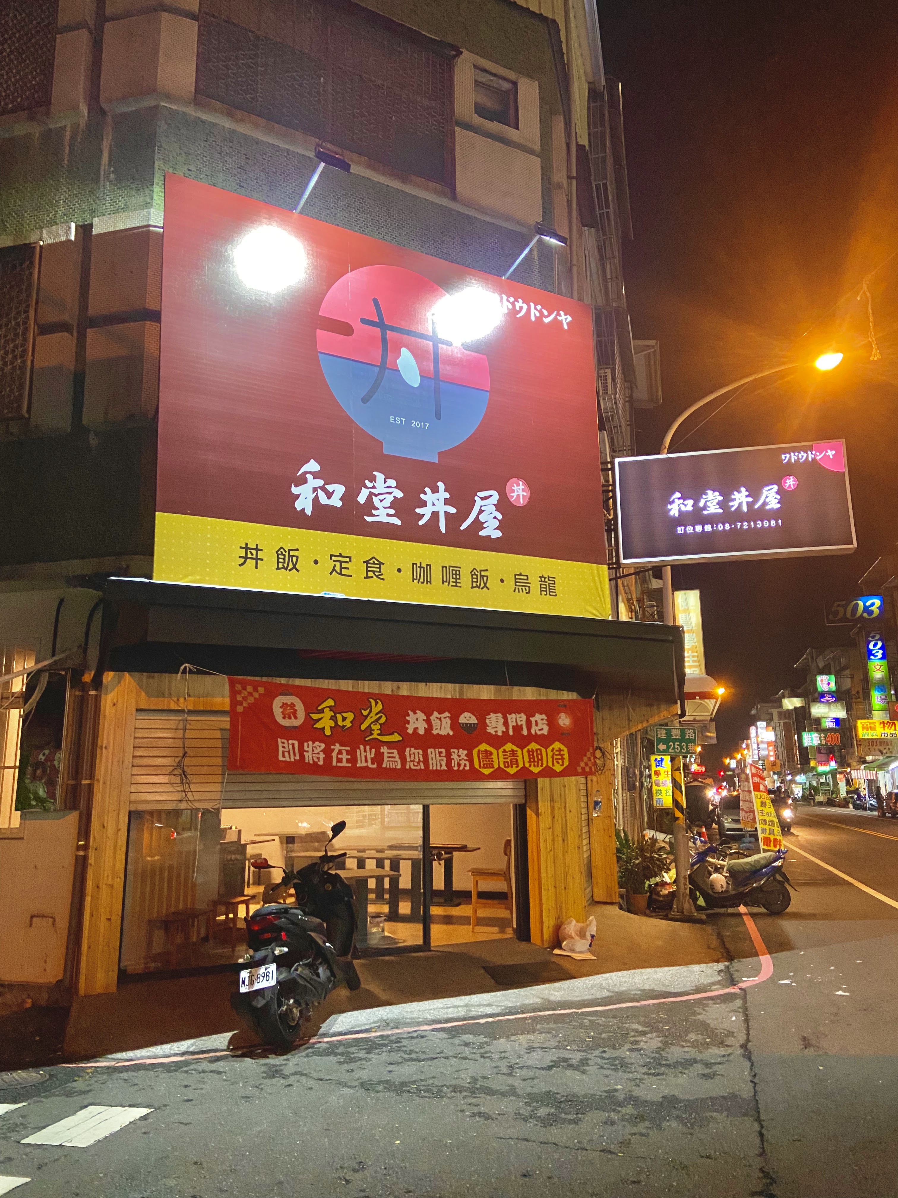 這張圖片是一家名為和堂丼屋的餐廳外觀，主打丼飯、定食、咖哩飯及烏龍麵。店招明亮顯眼，門口有機車停放，還有紅色布條預告即將開幕。圖片未見明顯浮水印。