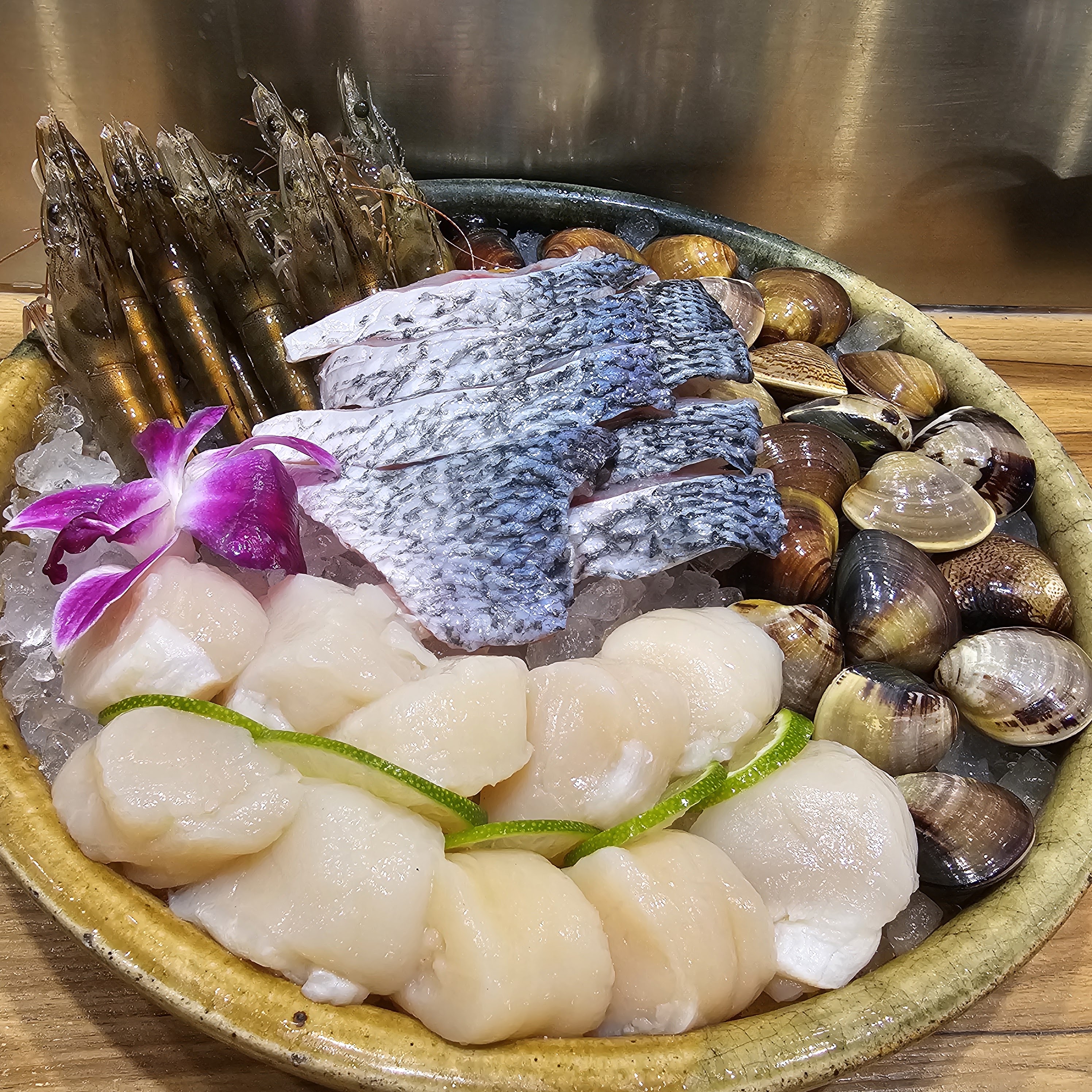 這張圖片是一盤新鮮的海鮮拼盤,內容包含蝦子、魚片、干貝和蛤蜊,擺放在碎冰上並點綴紫色蘭花。圖片整體色彩鮮明,沒有浮水印。