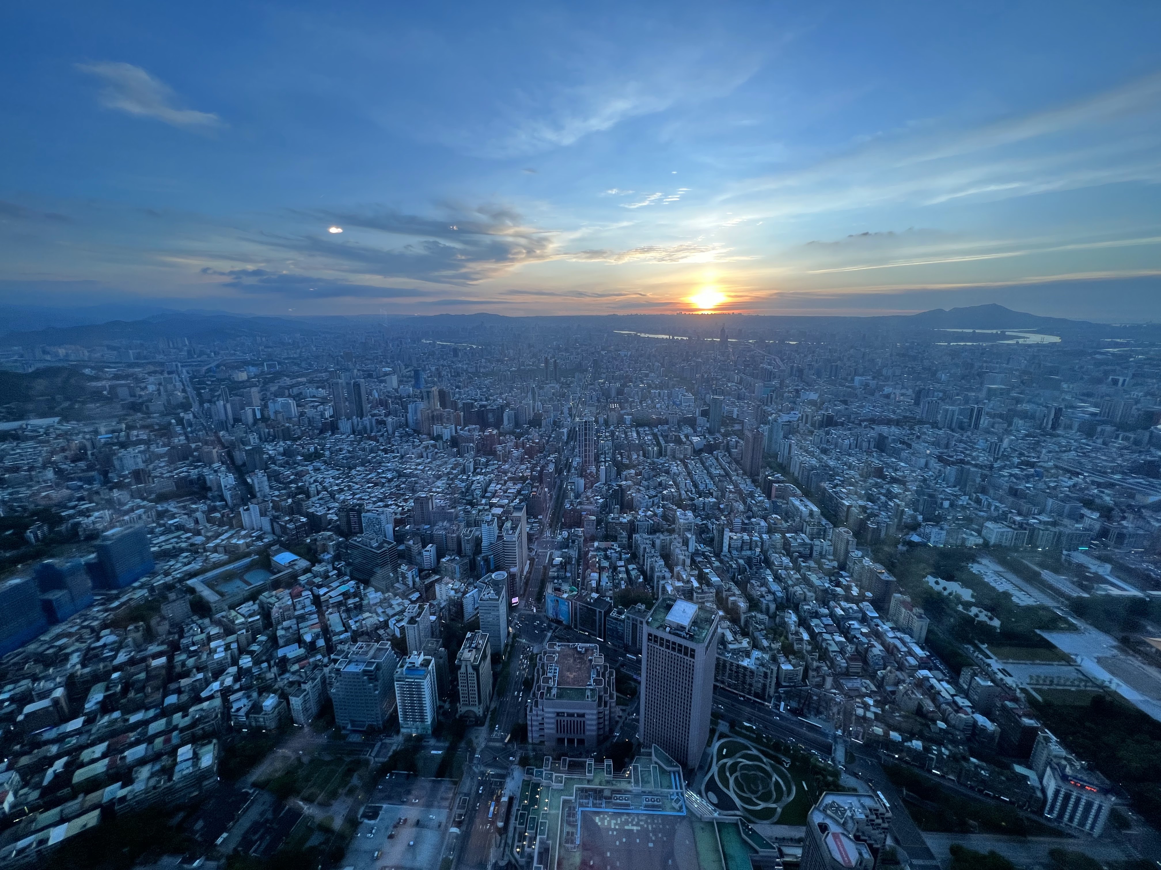 夕陽下的城市高空景觀，高樓林立、道路交錯。