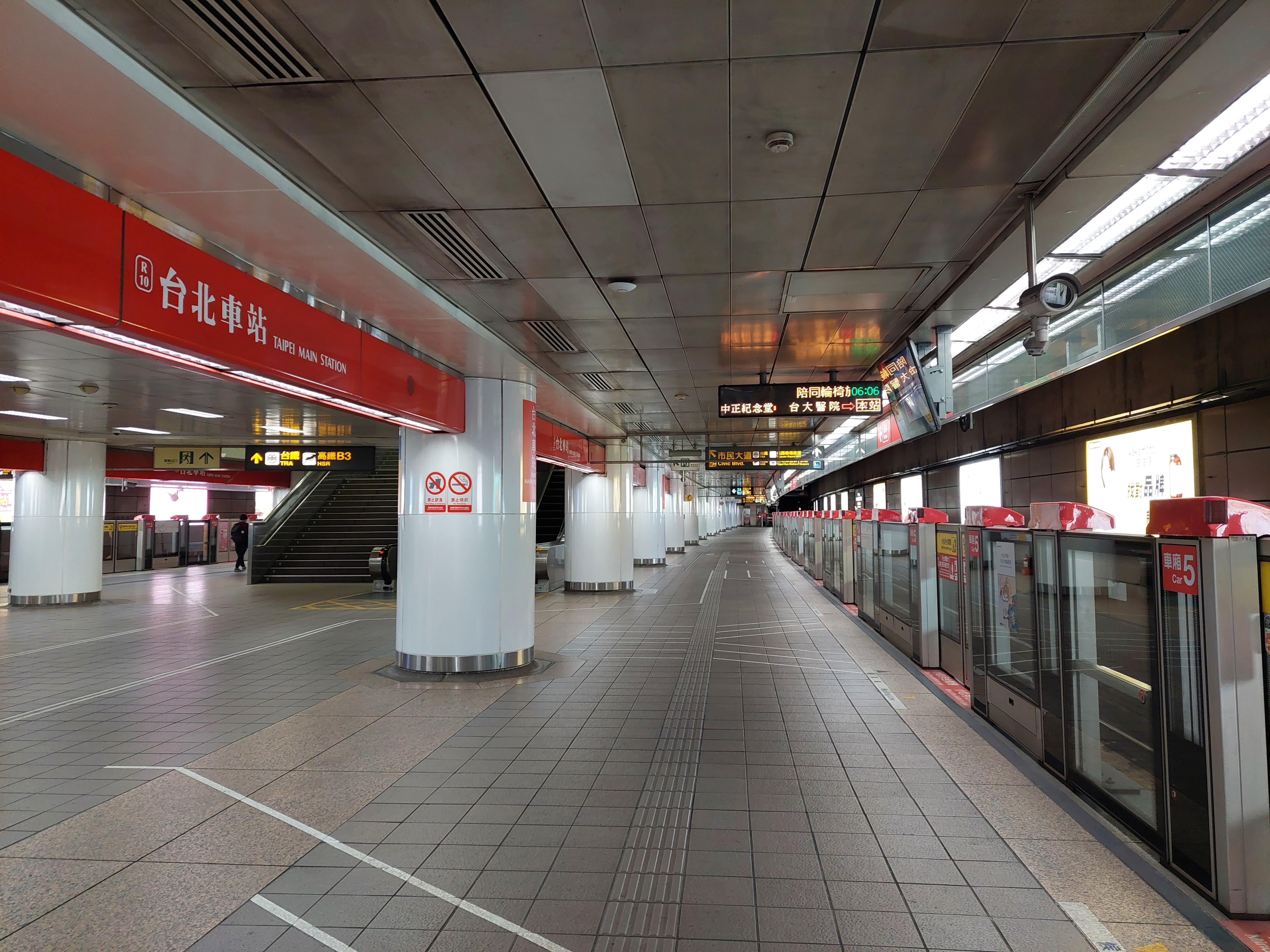 台北捷運台北車站月台區域，有紅色標示牌、月台門、自動扶梯和電子資訊看板
