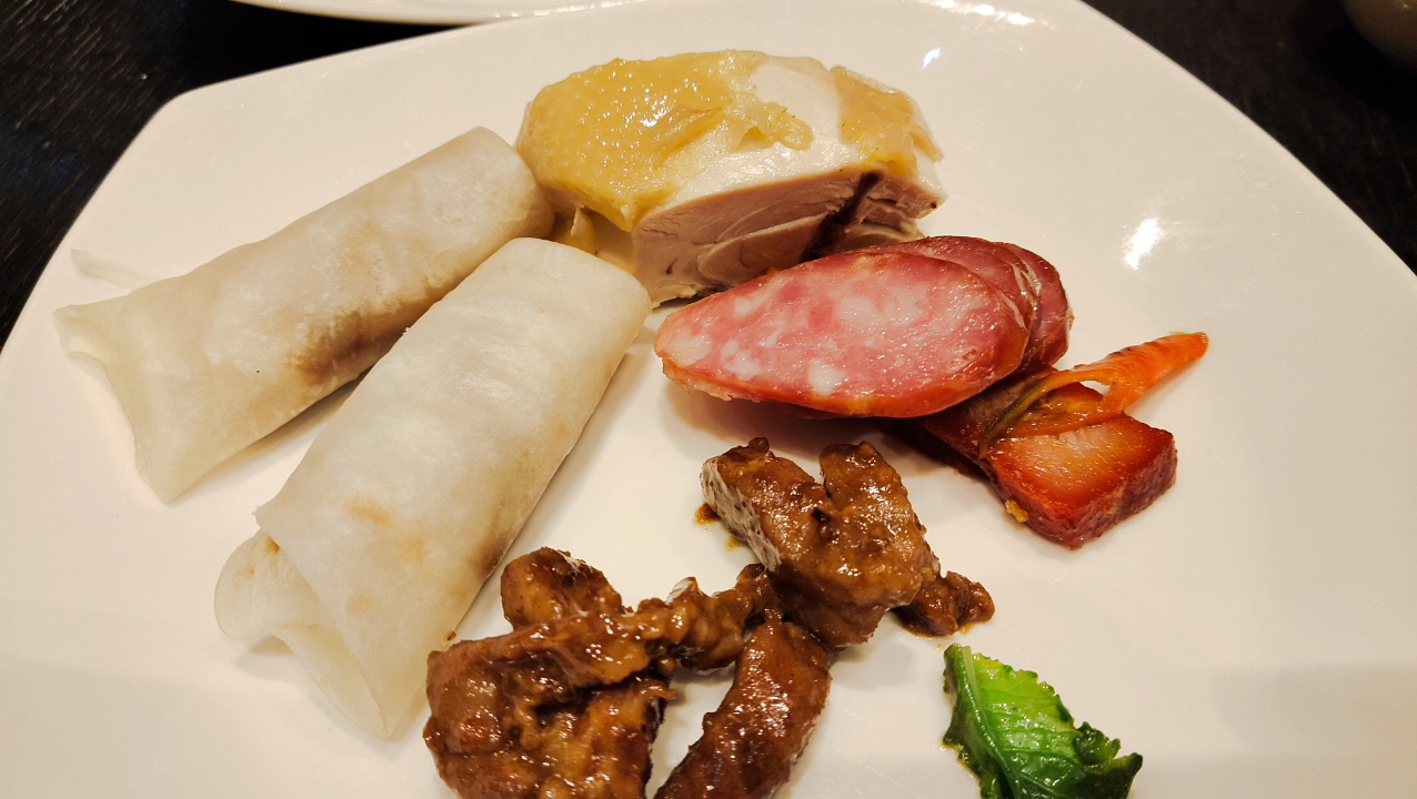 這張圖片主要有鴨肉捲、白切雞、臘腸、叉燒、炒牛肉和一點青菜，都是常見的中式菜餚，色香味俱全。圖片無明顯浮水印。