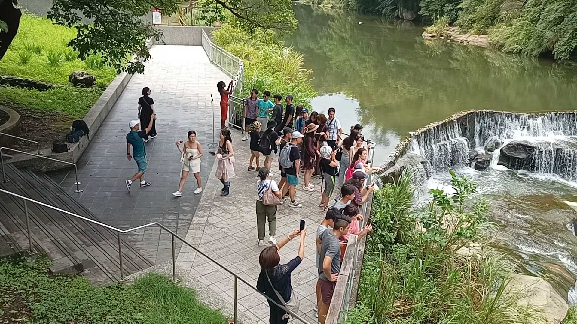 遊客在欄杆旁欣賞瀑布與溪流