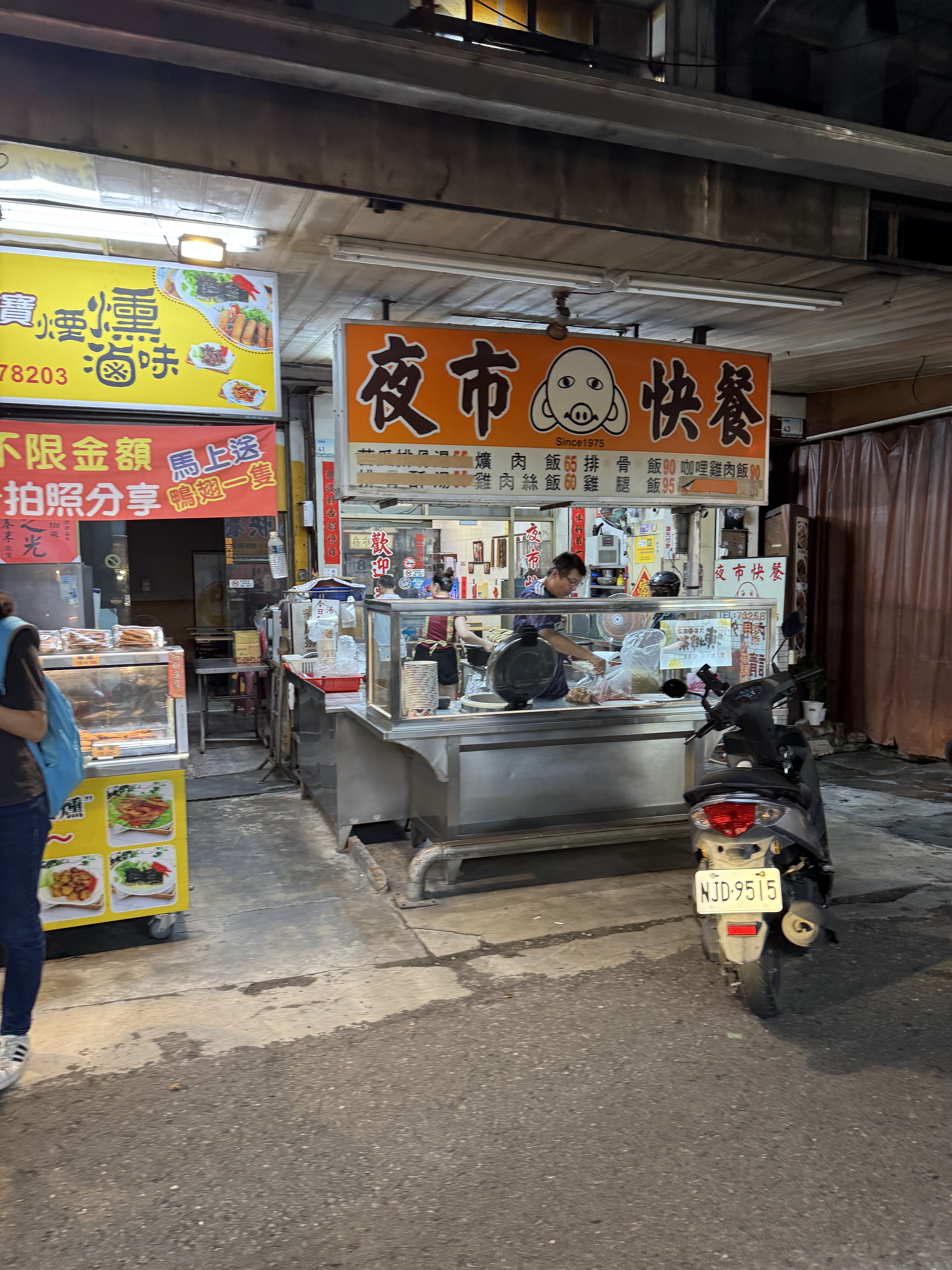 夜市快餐攤位橘色招牌與工作人員備餐畫面