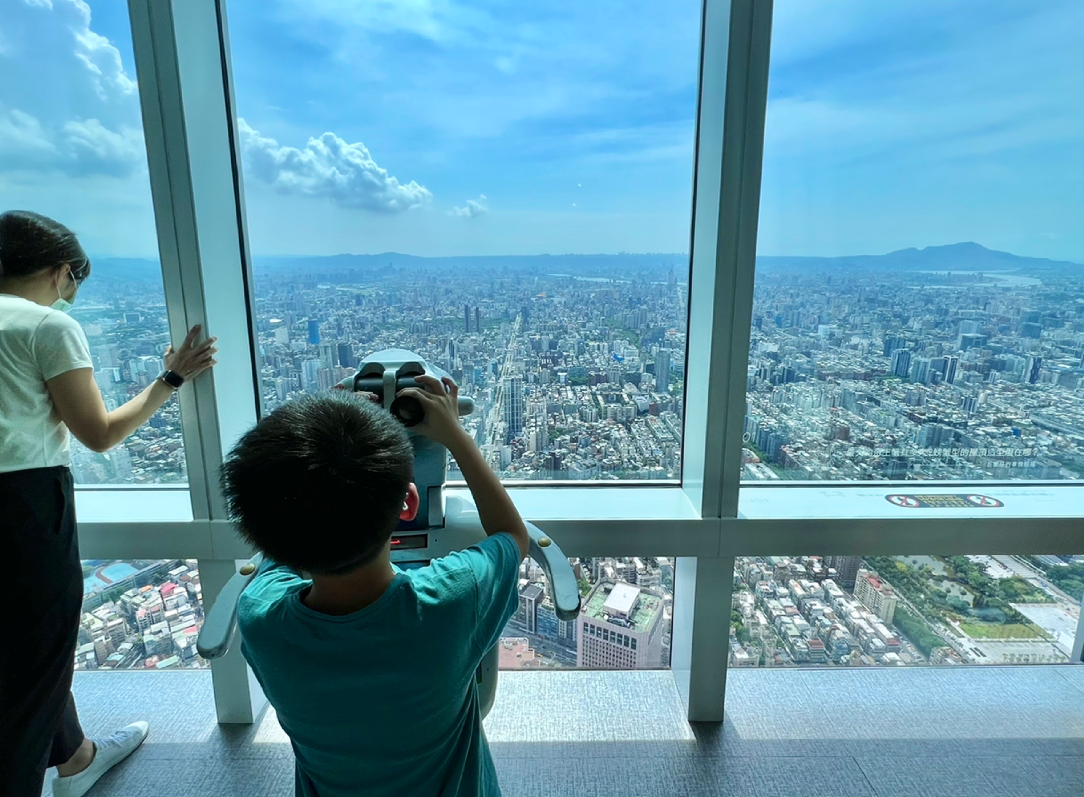 兩人在高樓觀景台上俯瞰城市景色。
