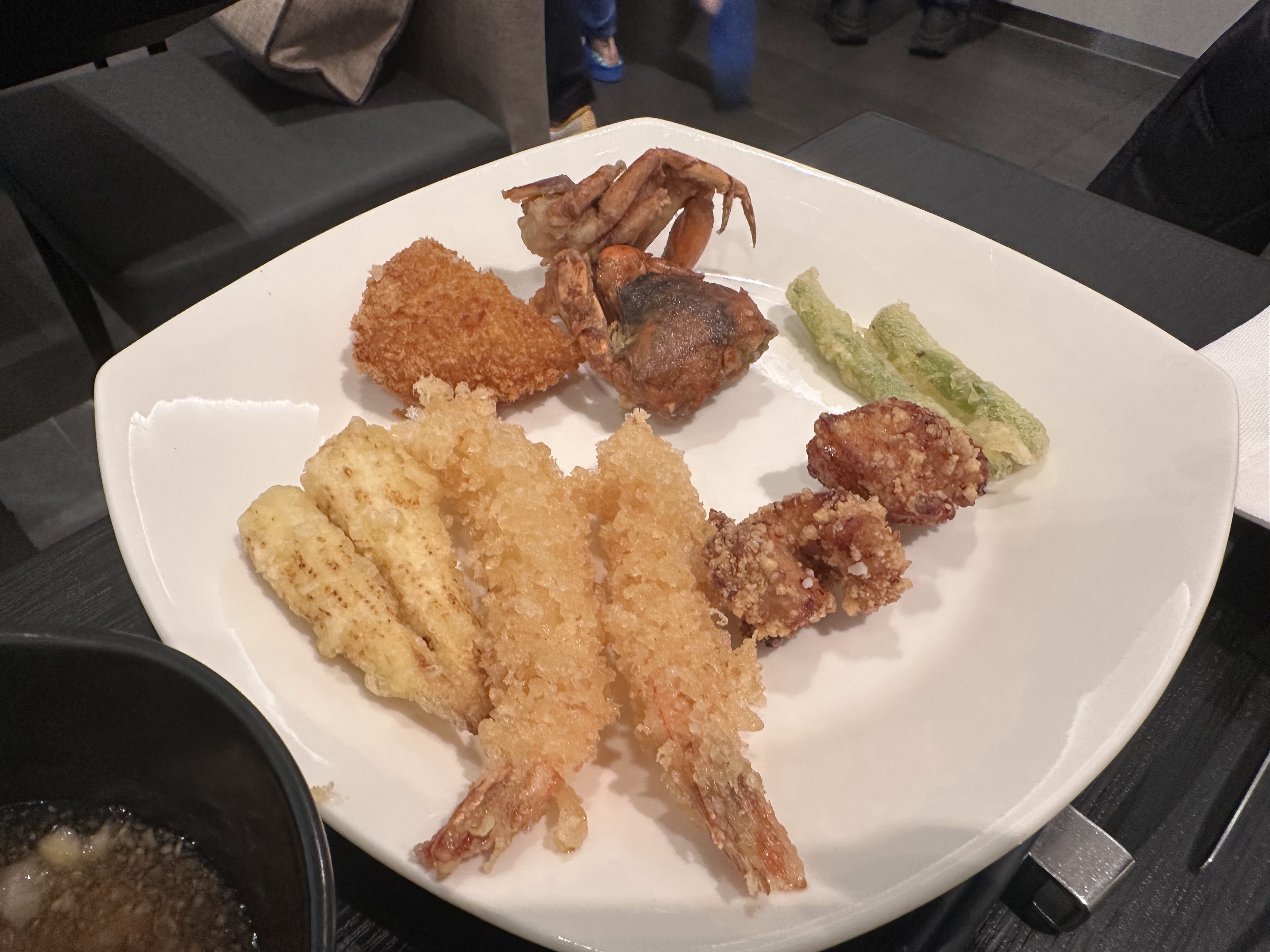 這張圖片主要是一盤日式炸物拼盤，有炸蝦、炸蟹、炸魚、炸雞塊與炸蔬菜，色澤金黃酥脆，擺放在白色方盤上，畫面乾淨無浮水印。