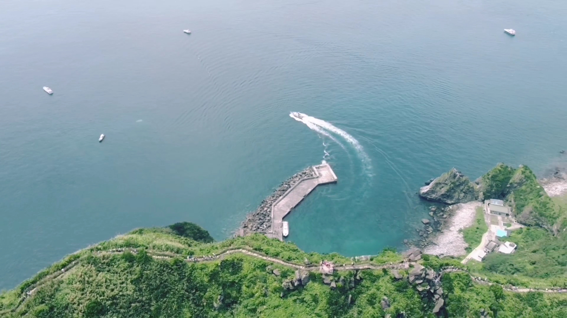 綠意盎然的海岬與港灣，海面上可見多艘船隻