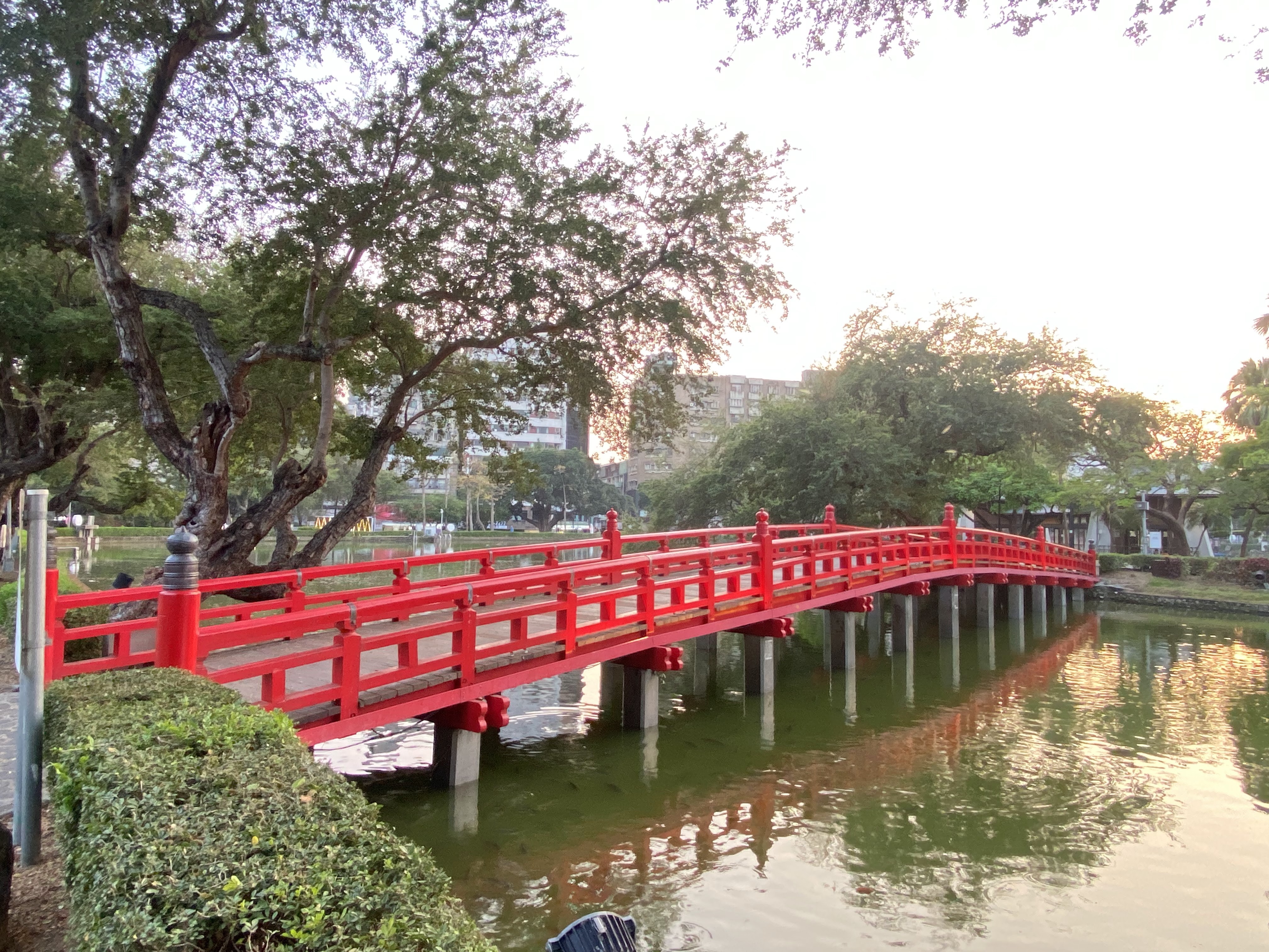 夕陽下的鮮紅拱橋與池塘