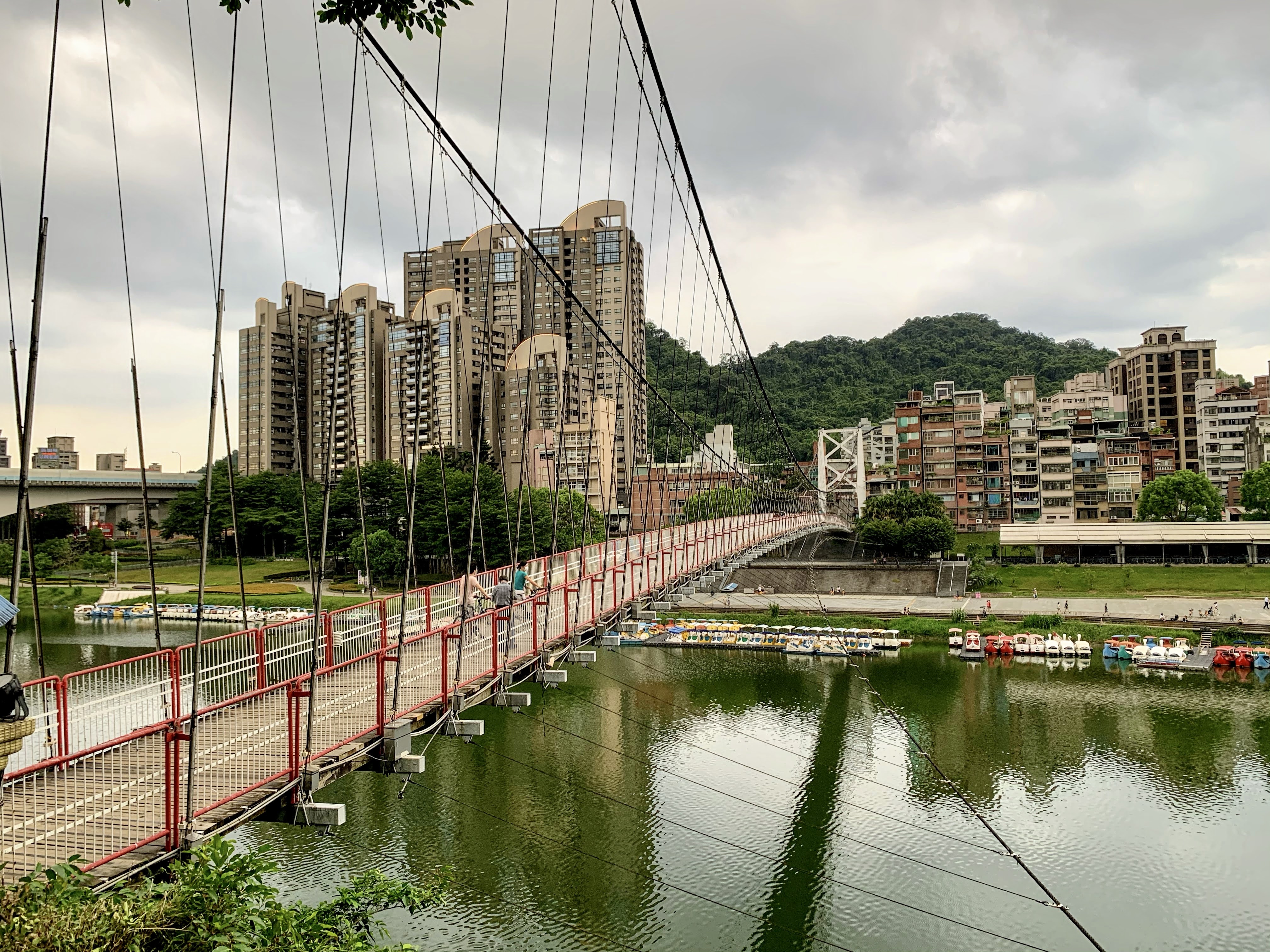 紅色吊橋橫跨河面，河上有多艘天鵝船。