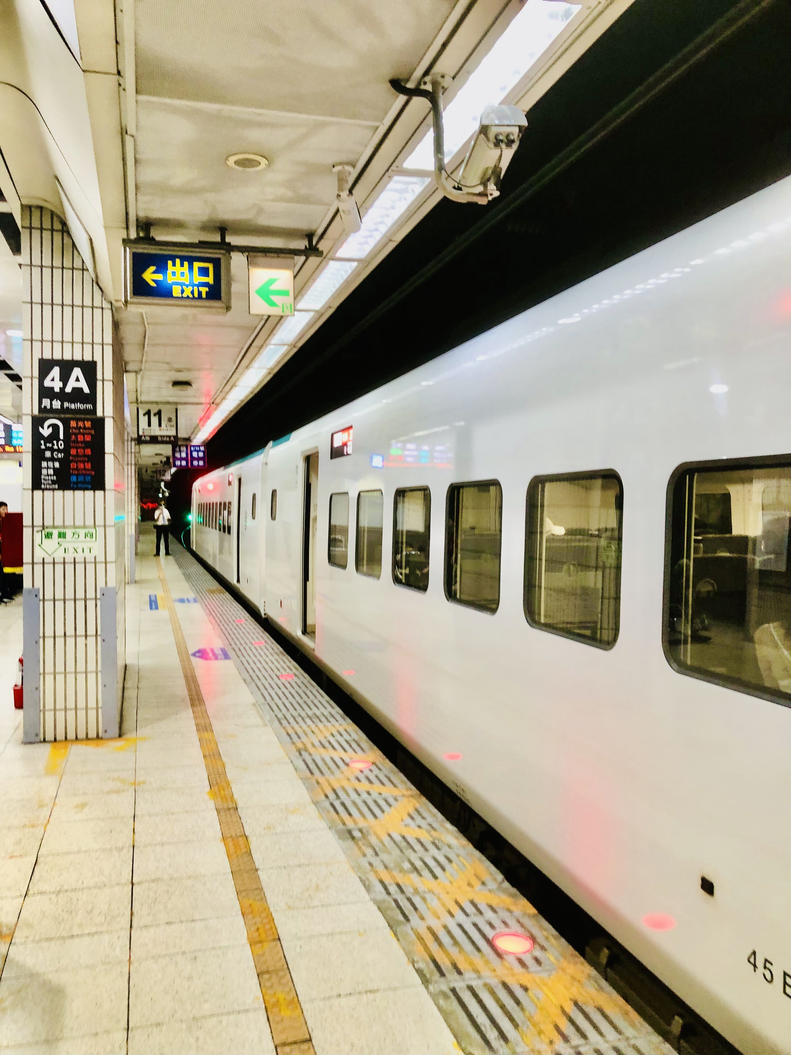 火車站月台，中央是一列白色列車，月台地面標示清楚