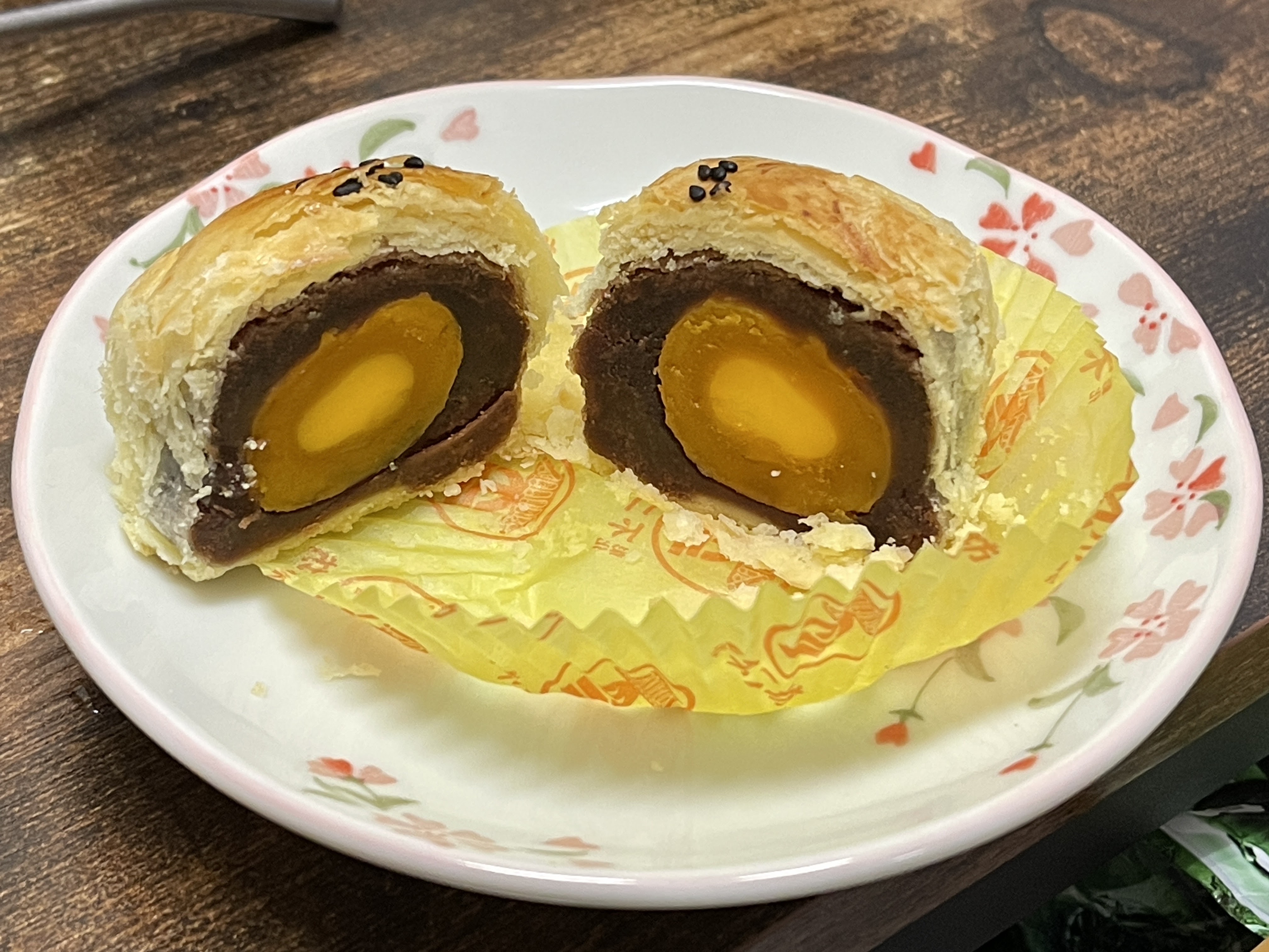 蛋黃酥切面擺在花紋瓷盤與黃色紙杯上