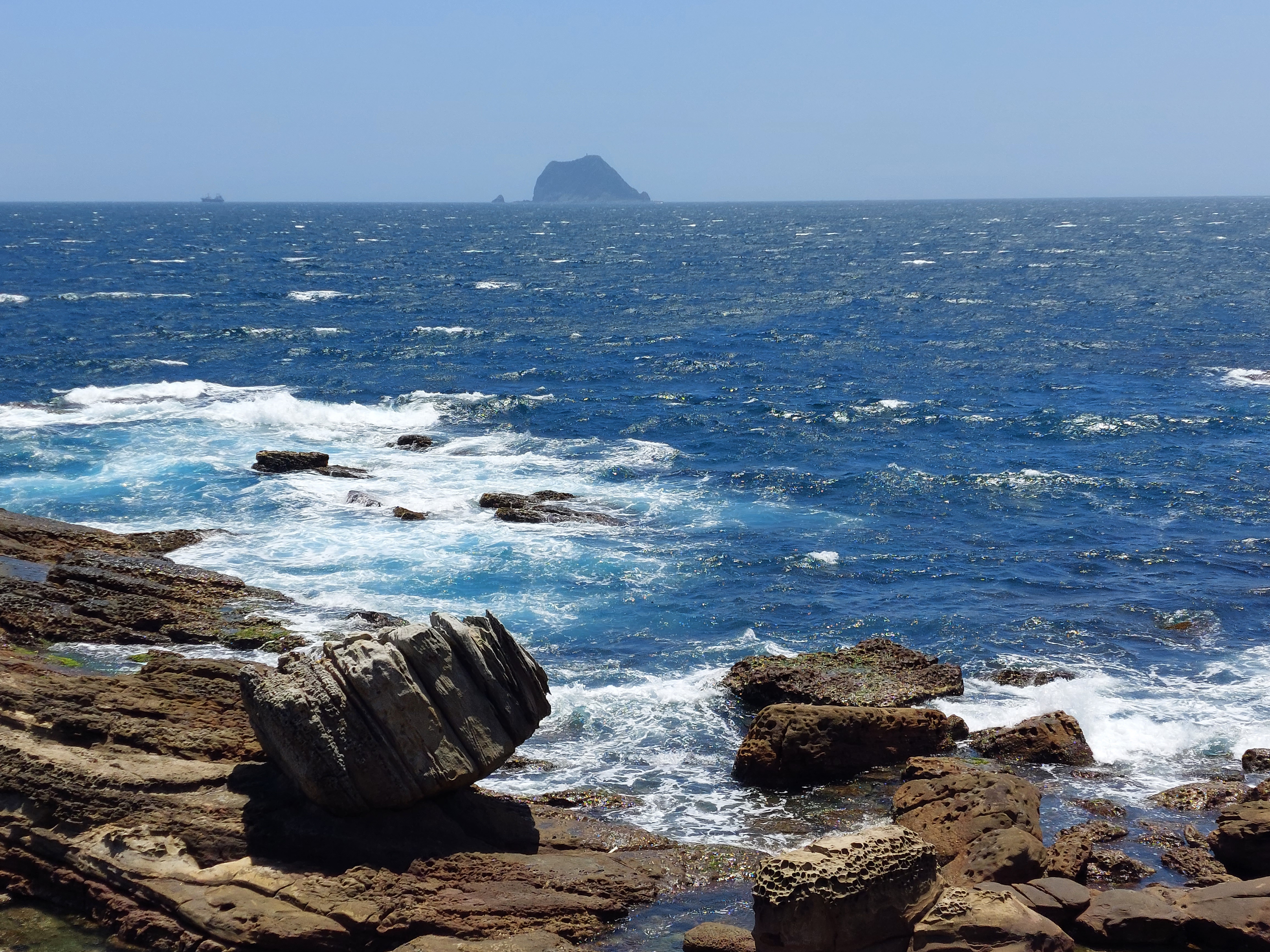 蔚藍海洋、奇岩怪石與遠方小島的自然海岸景觀