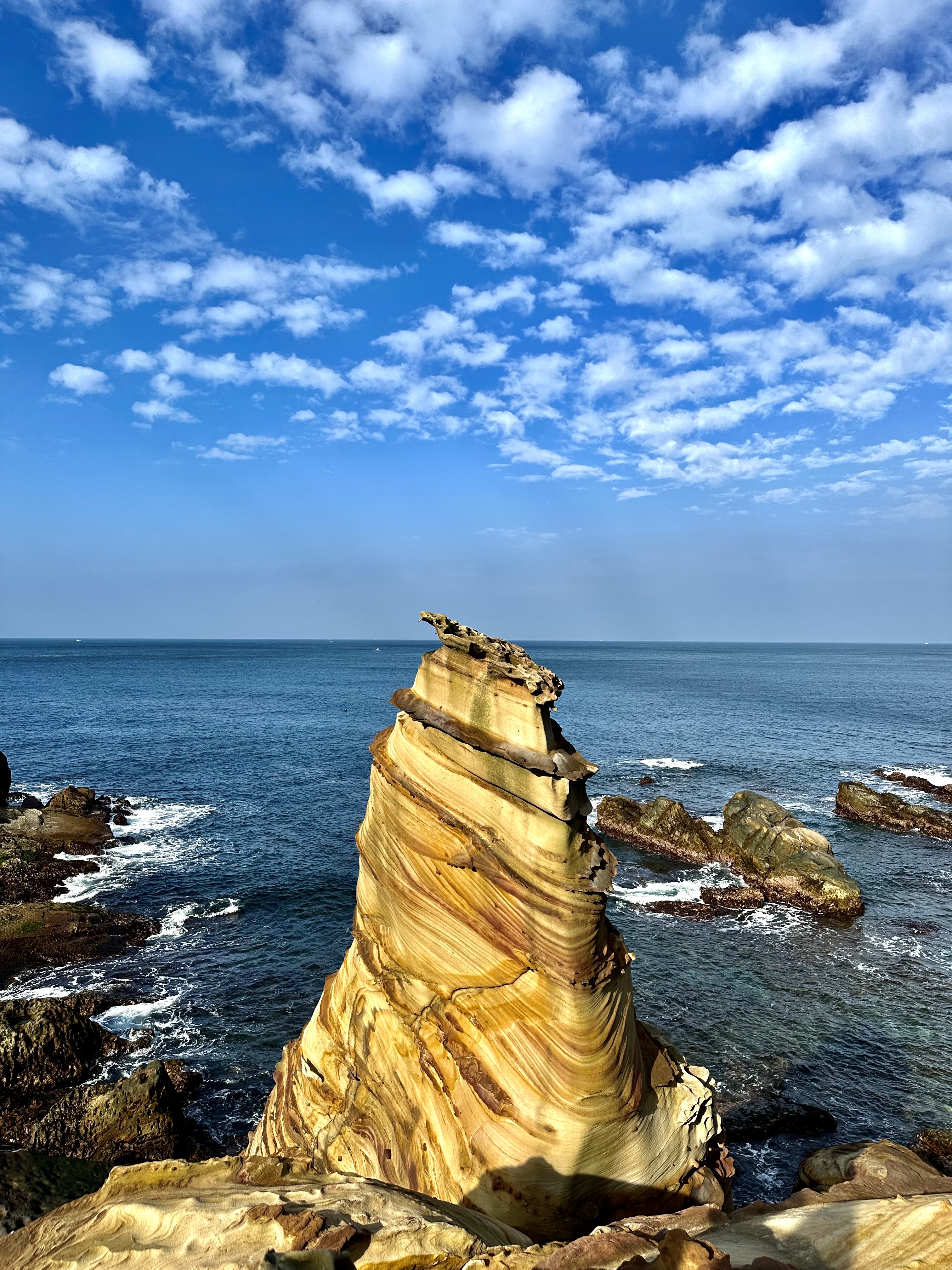 造型獨特、色彩分明的岩石地景，位於藍色大海邊。