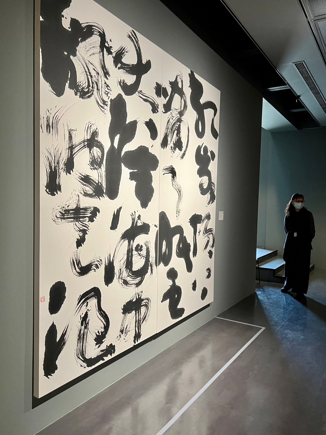 畫廊牆面上的大型抽象水墨書法作品與參觀者