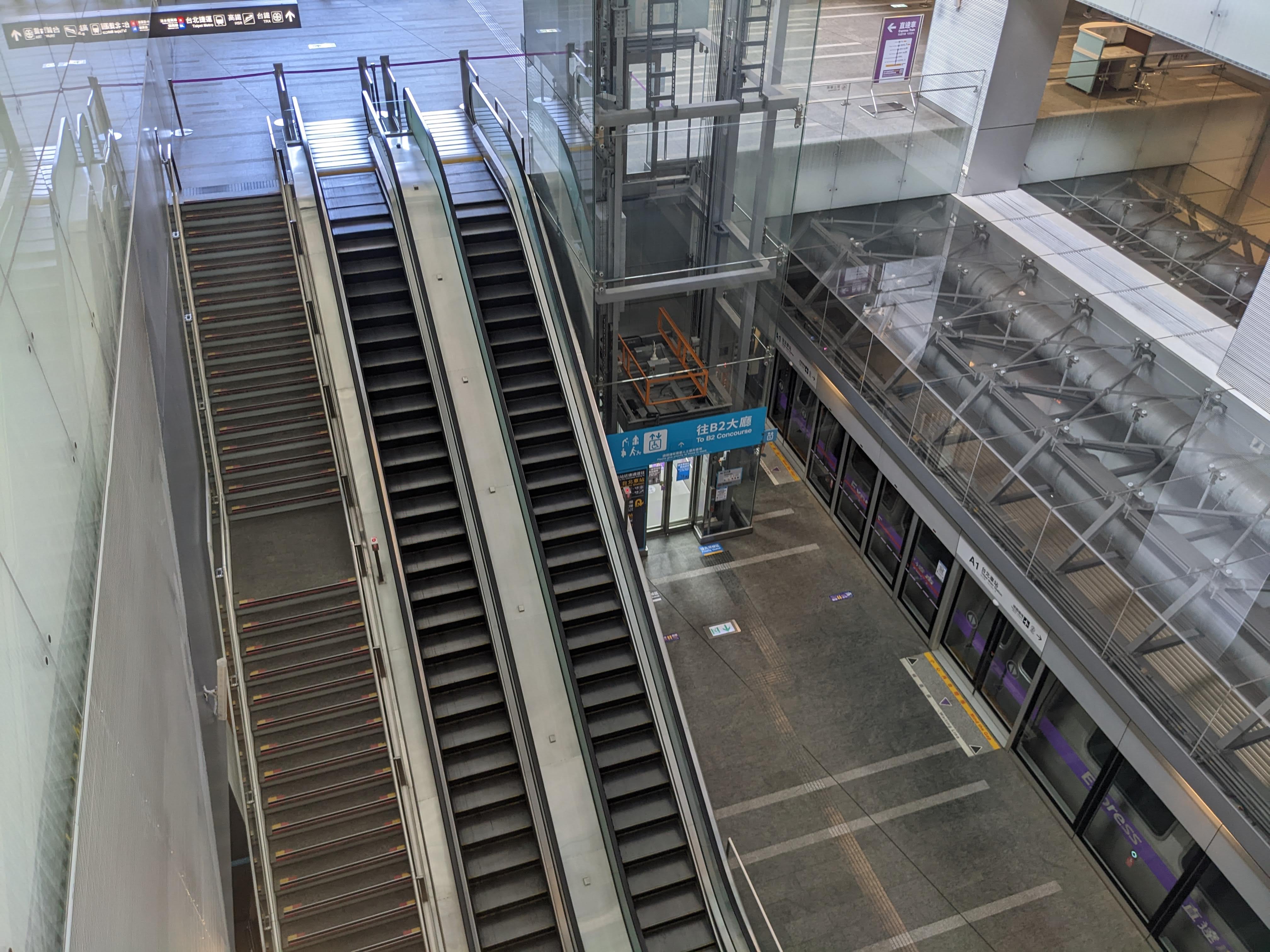 現代化車站月台區域，有樓梯、手扶梯和電梯，環境整潔明亮