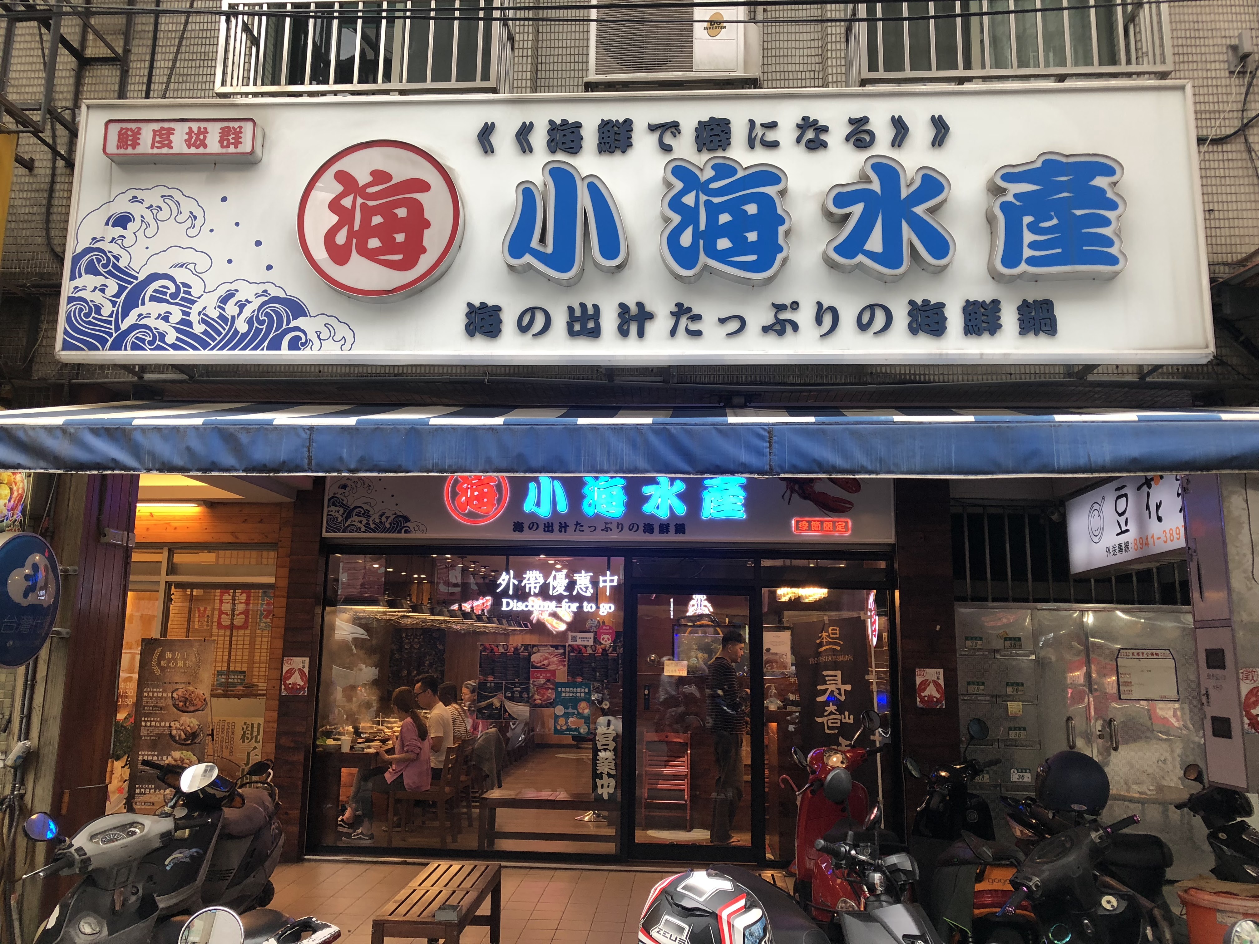 這是一家名為『小海水產』的海鮮餐廳門口,店面有明顯的招牌,主打海鮮火鍋,門前停有多輛機車。圖片無浮水印。