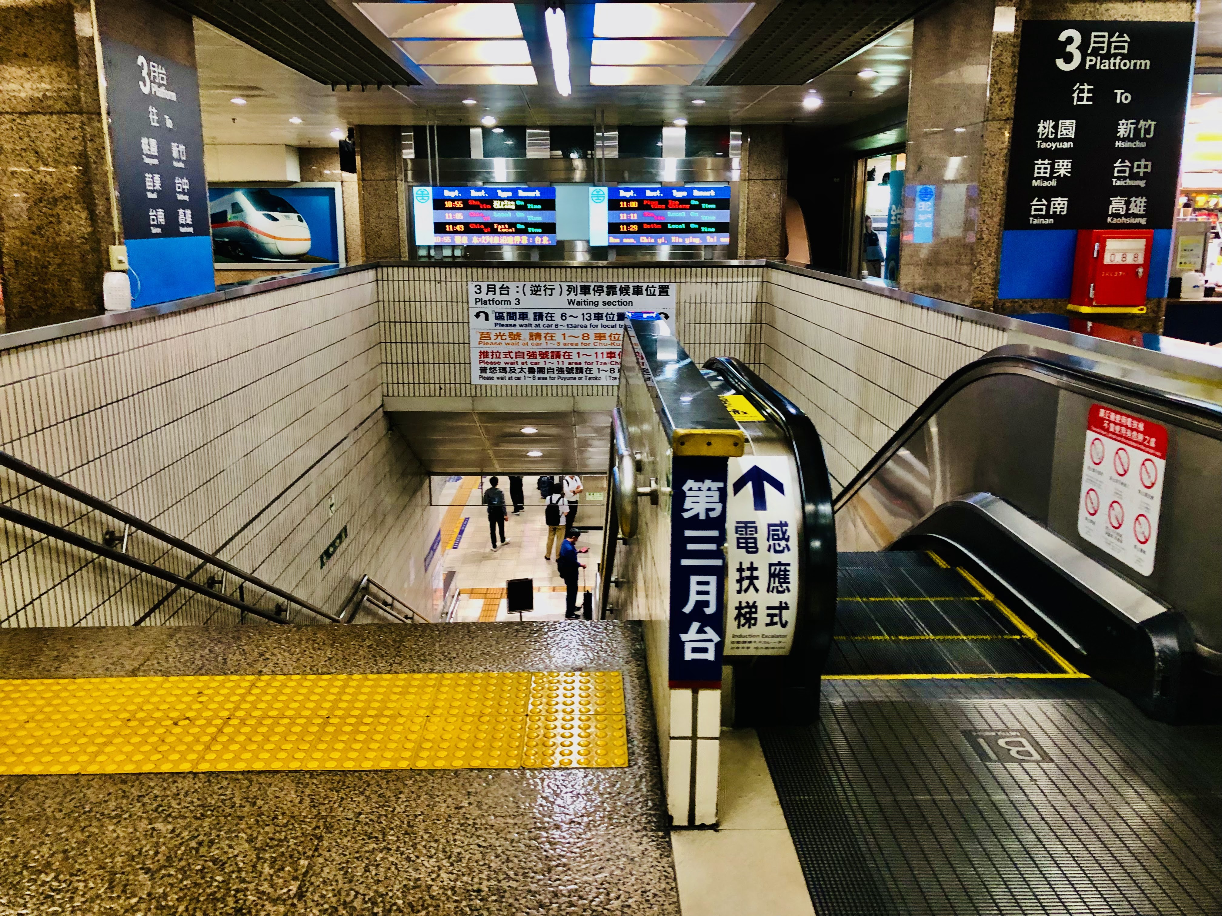 台灣高鐵或台鐵月台入口，有手扶梯、樓梯與列車資訊顯示