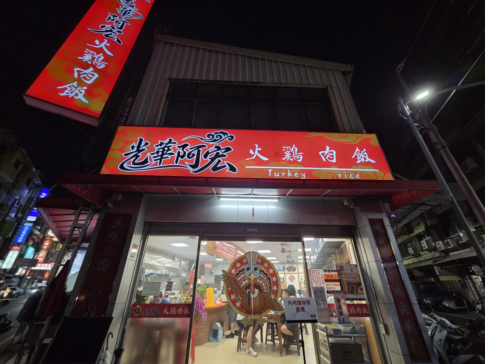 光華阿宏火雞肉飯總店夜間店面,紅底招牌Turkey rice,火雞吉祥物立牌