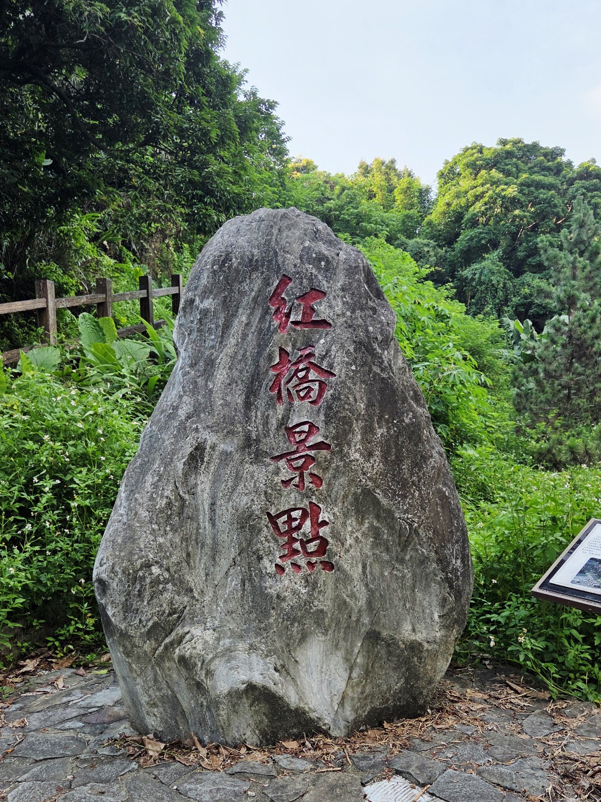 紅橋景點石碑立於步道旁，周圍綠意環繞