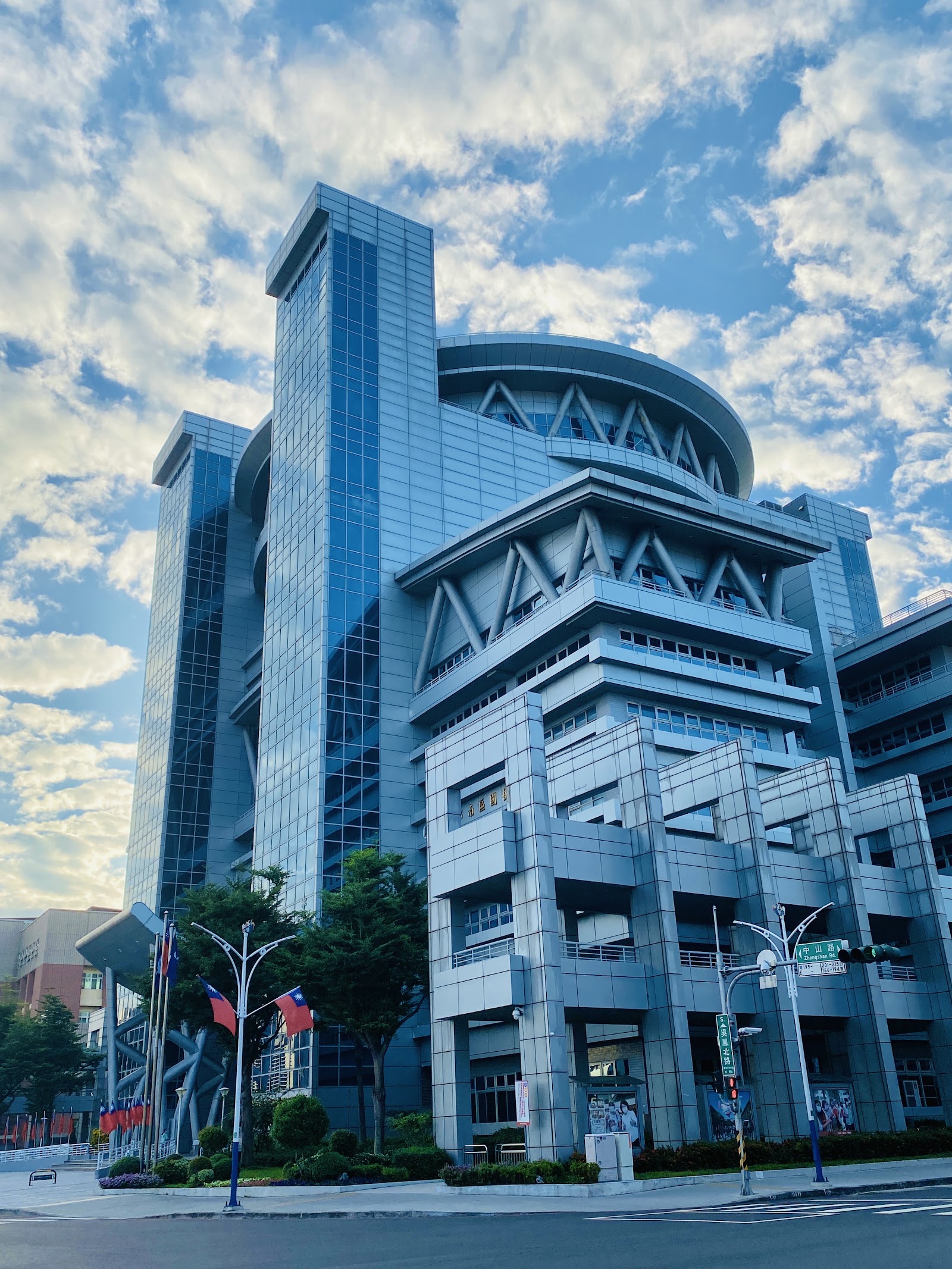嘉義市政府藍天白雲下現代玻璃帷幕建築，國旗飄揚