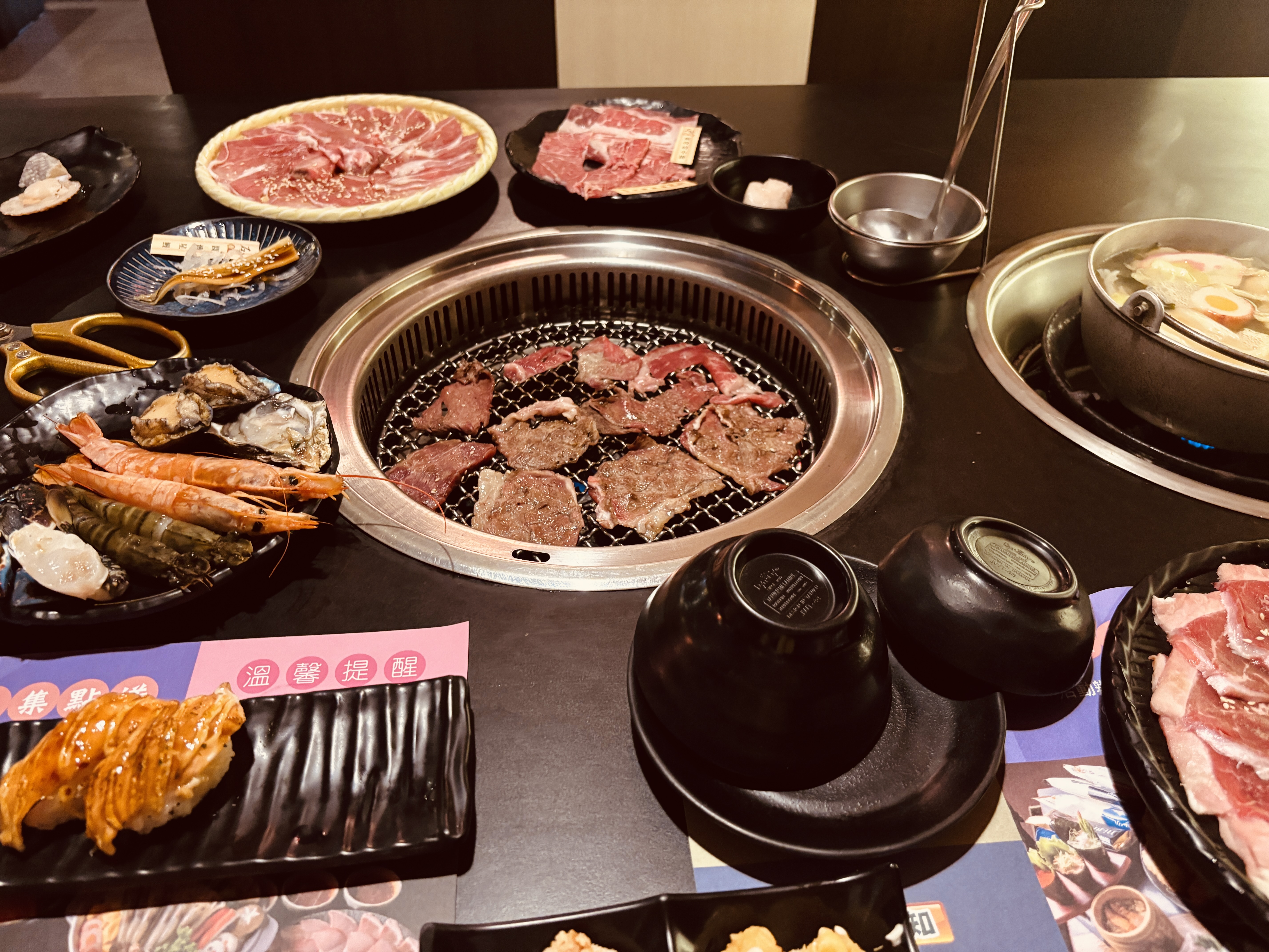 桌上擺滿生牛肉海鮮壽司與火鍋