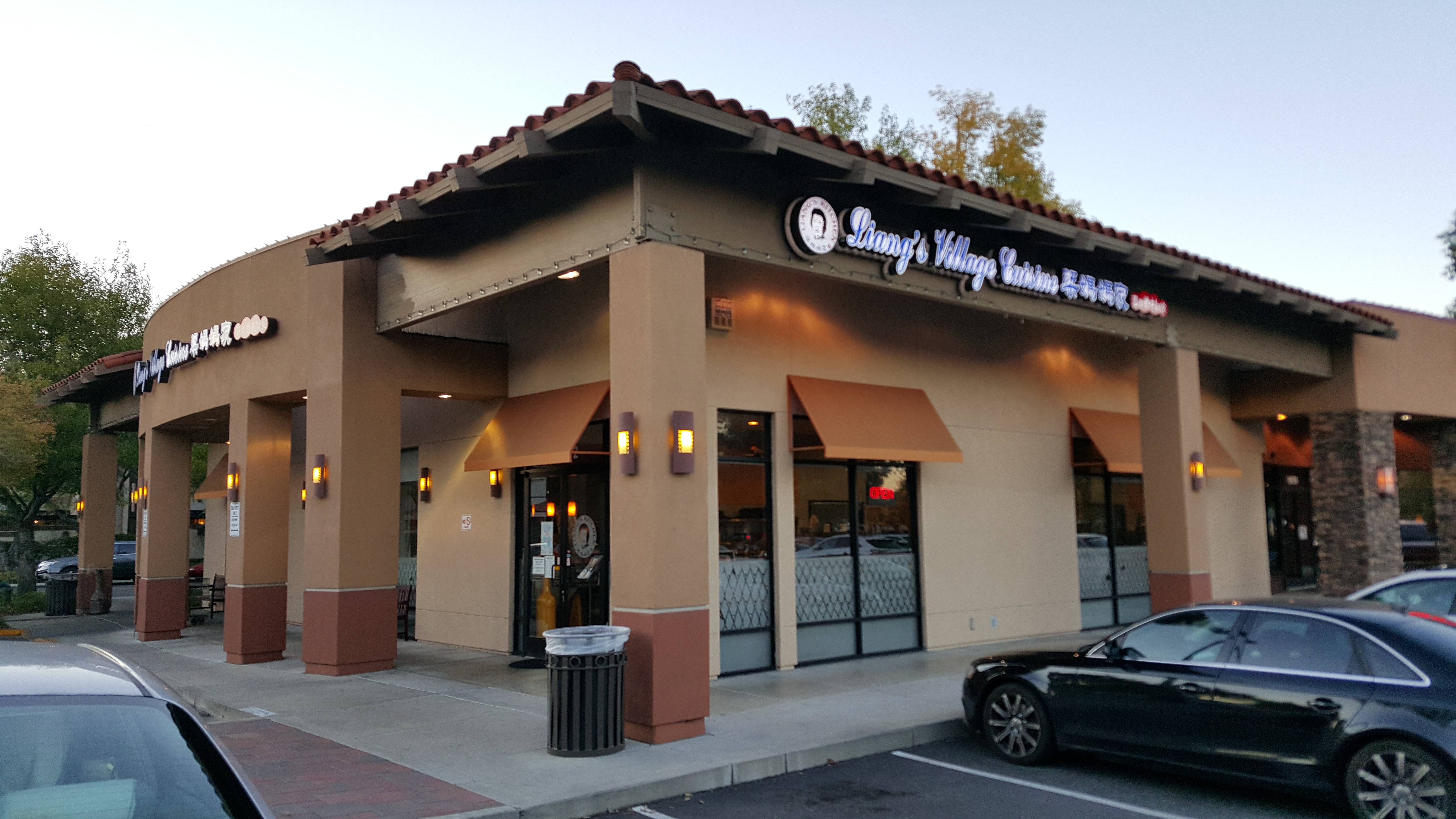 這張圖片顯示一家名為Liang's Village Cuisine的餐廳外觀,外牆具有簡約現代風格,門口有垃圾桶及大型玻璃窗,並沒有看到浮水印。