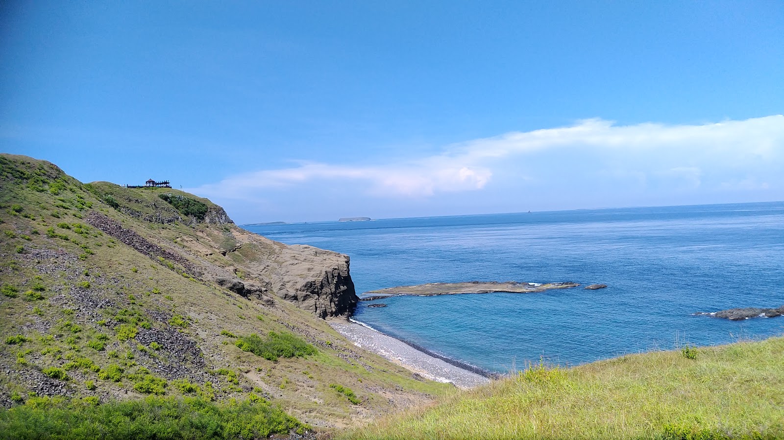 澎湖七美牛姆坪-崖頂大草原俯瞰海灣礫石灘,遠方小觀景亭立