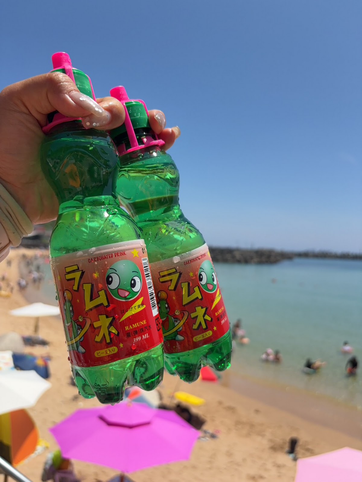 海灘第一間手持波子汽水，背景為沙灘遮陽傘