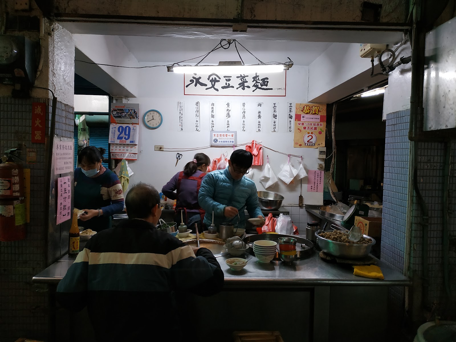 永安豆菜麵攤位招牌與忙碌備餐身影,藏身白河早市裡的銅板美食店