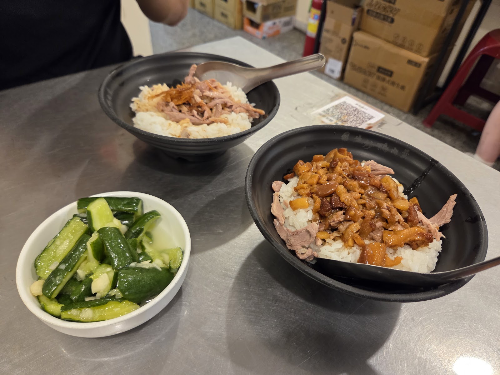 兩碗鴨肉飯與小黃瓜涼拌小菜,不鏽鋼桌面