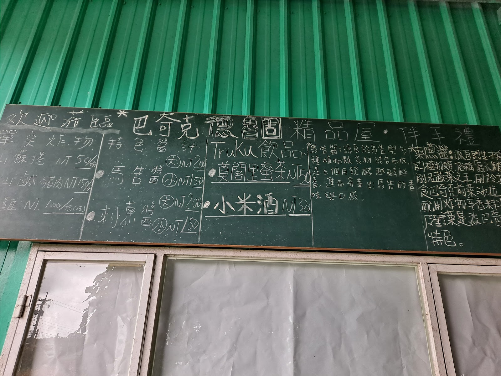巴奇克竹坊綠色鐵皮牆上手寫黑板菜單，列出Truku飲品莫爾里蜜茶與小米酒