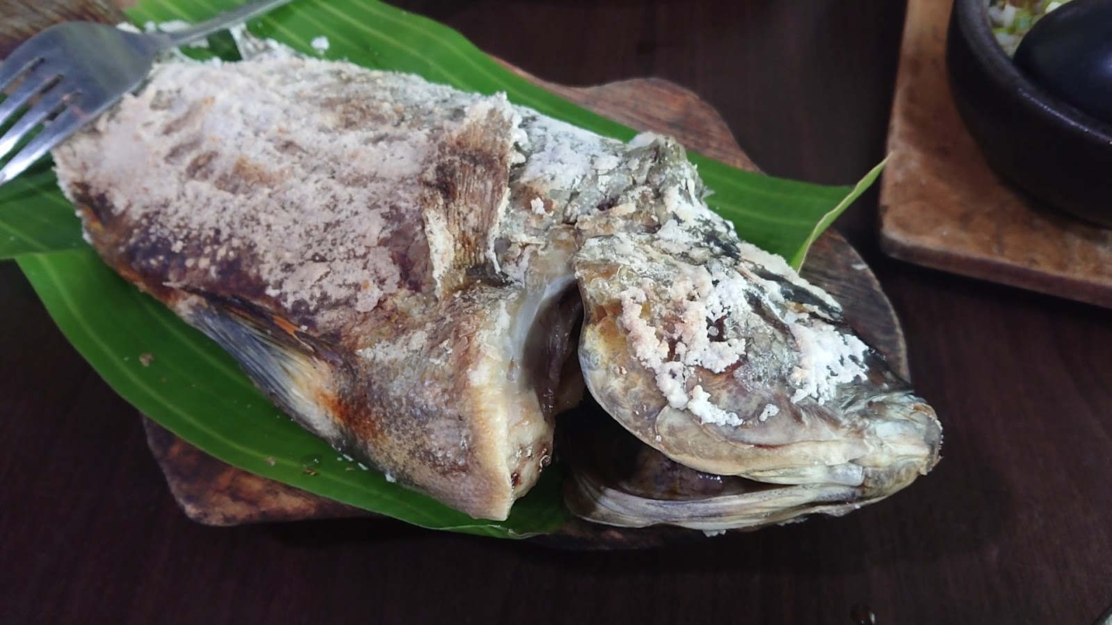 巴奇克竹坊月桃葉上盛裝鹽烤鮮魚，魚身覆蓋鹽殼烤痕