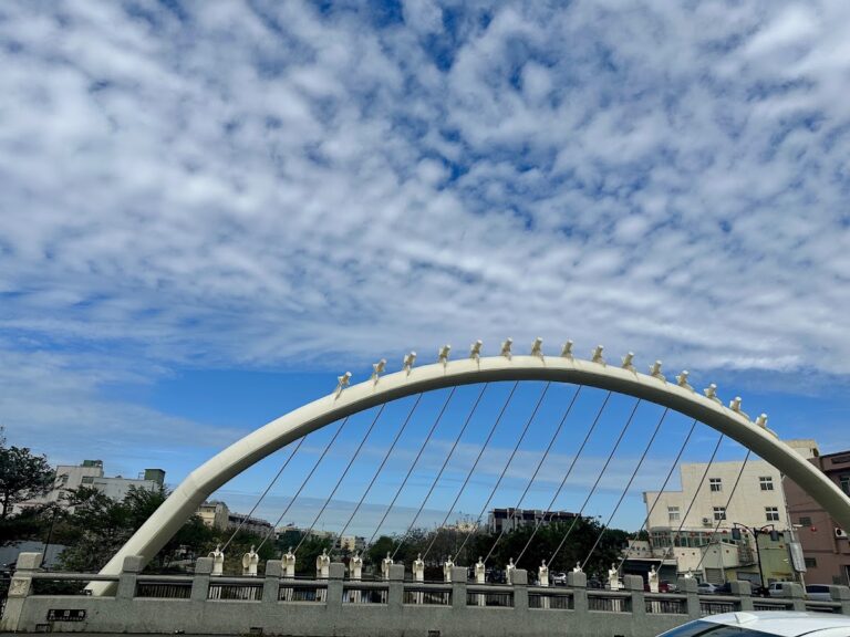 鹿港溪白色風帆橋｜鹿港溪白色風帆橋日間景致，弧形拱身與斜張鋼索在藍天白雲下十分搶眼