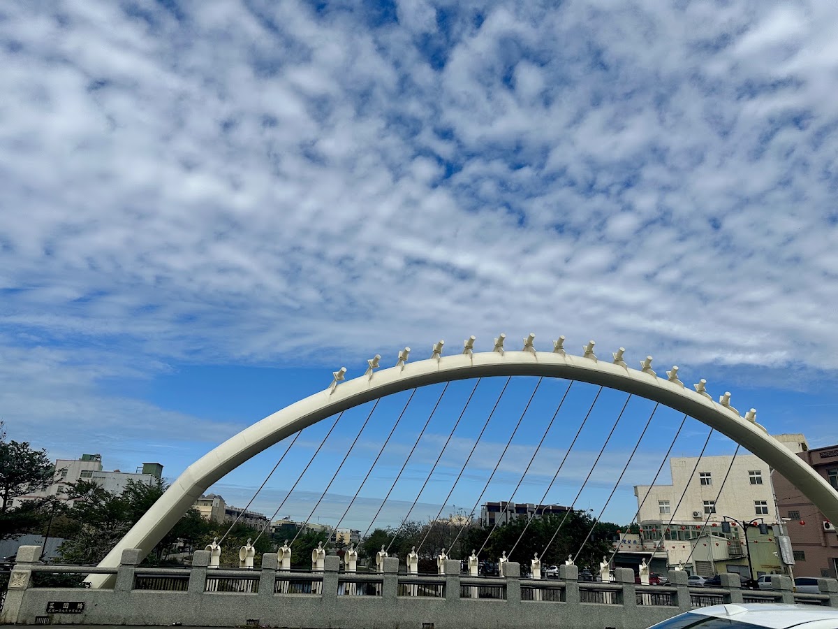 鹿港溪白色風帆橋|鹿港溪白色風帆橋日間景致,弧形拱身與斜張鋼索在藍天白雲下十分搶眼