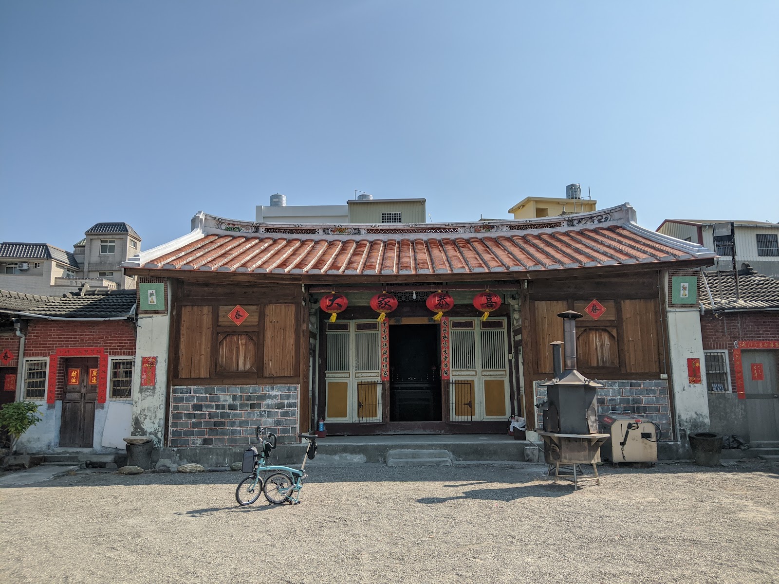 邱屋公廳忠實第正身紅瓦燕尾屋頂全景,廣場停著一台摺疊單車