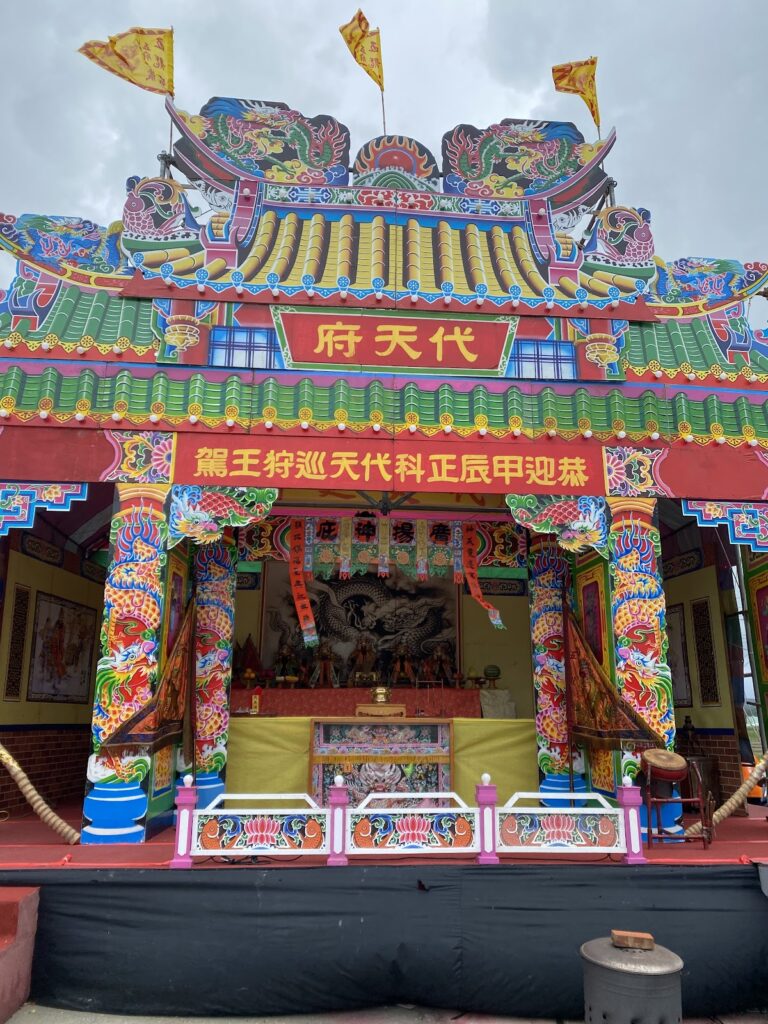 車城保力五龍宮－溫暖色彩的「代天府」牌樓全景，三角彩旗隨風飄揚