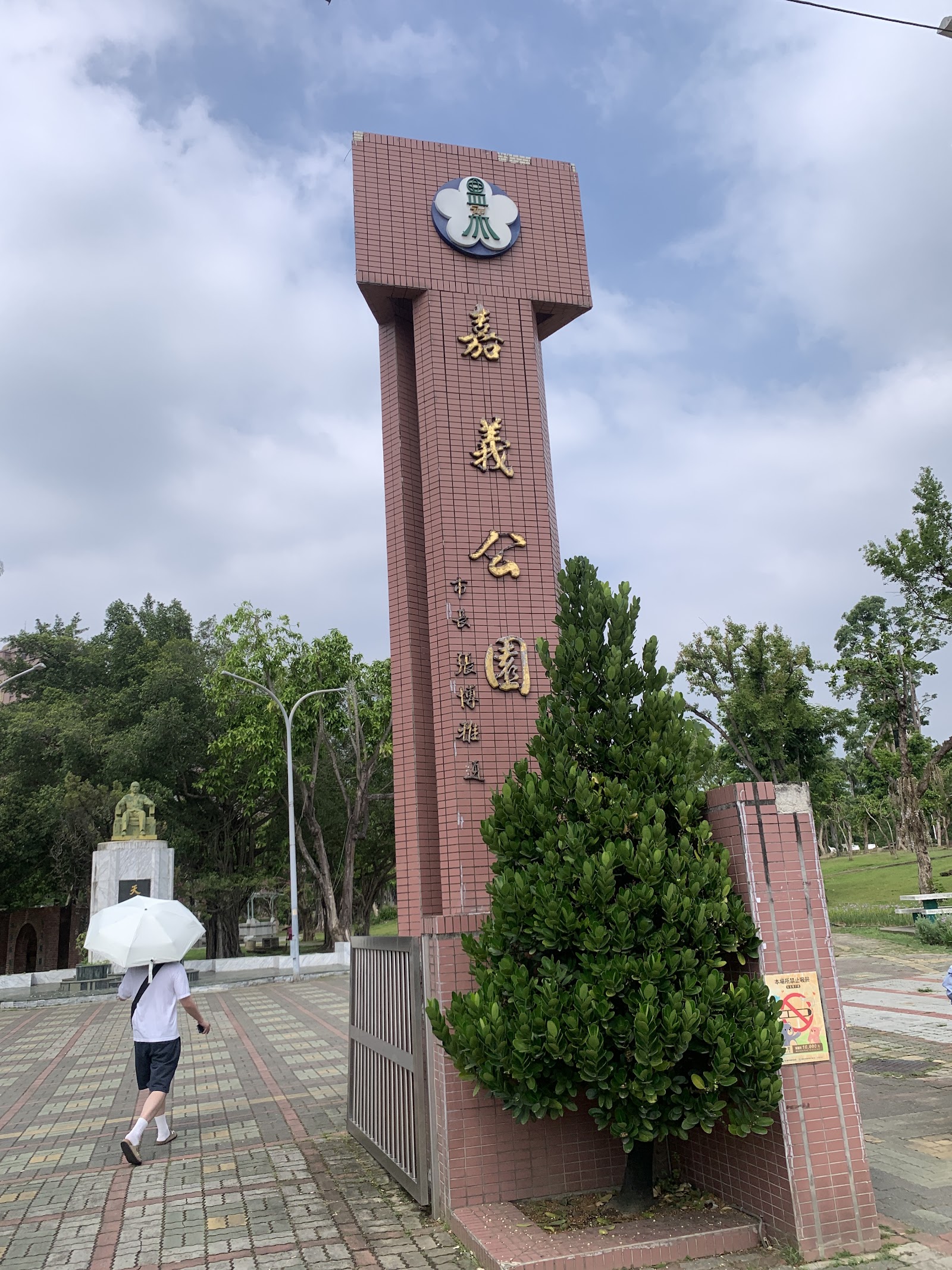 嘉義公園-嘉義公園入口牌樓,紅磚石柱刻著「嘉義公園」四個金字,藍天白雲作背景