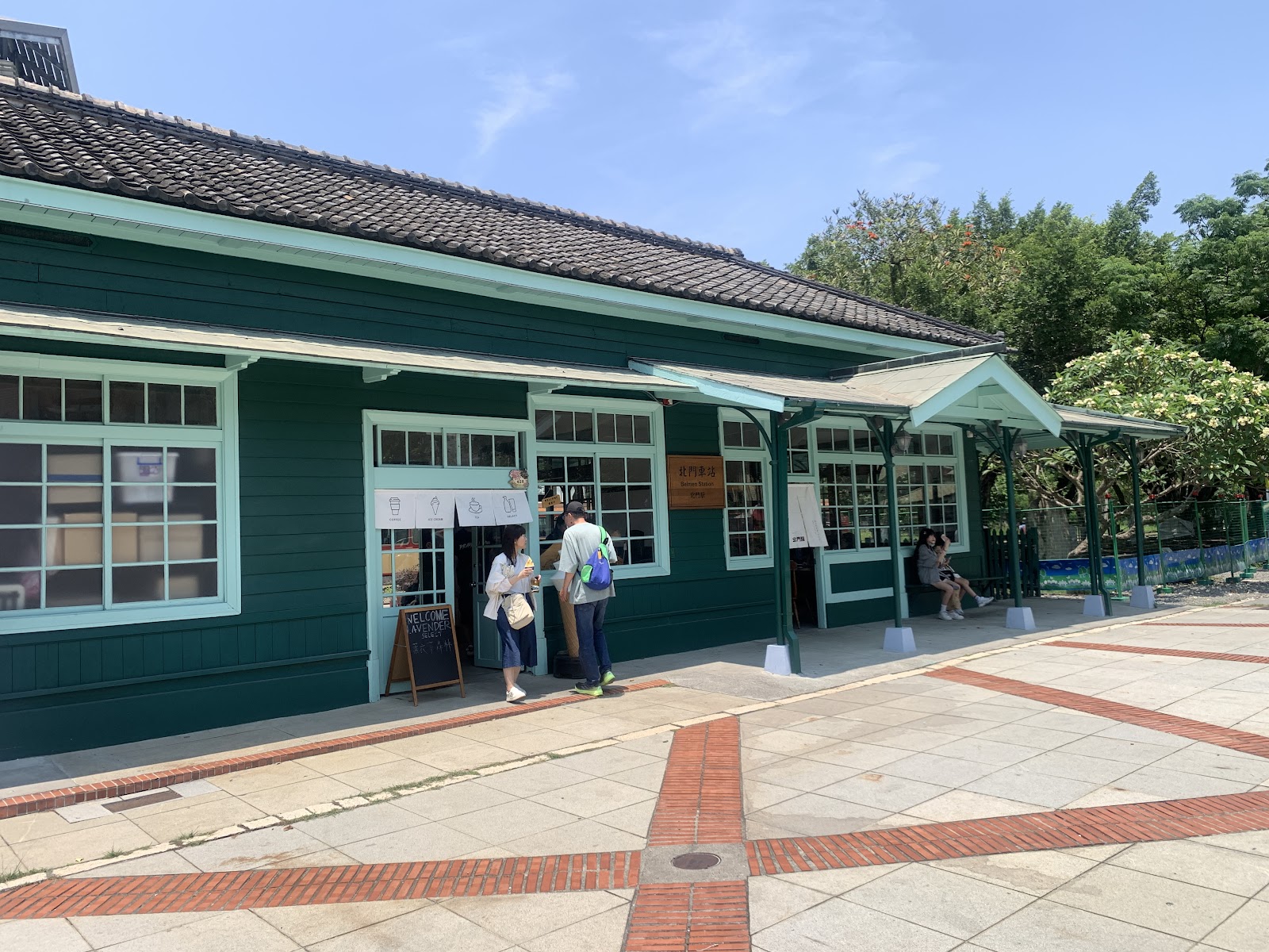 北門驛-北門驛綠色日式木造車站本體,屋簷下旅客正在選購小物,復古氛圍十足