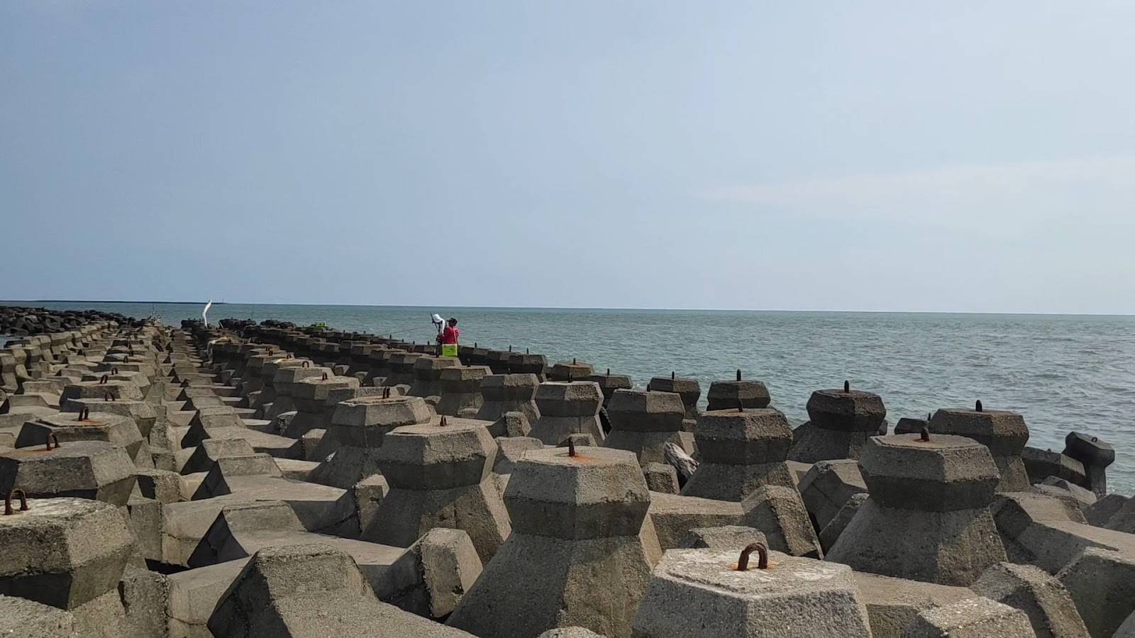鎮海公園白天消波塊海堤，遠方有釣客身影