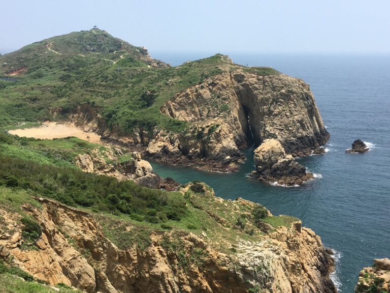神祕小海灣空拍海灣岬角與海蝕洞穴全景,金黃沙灘與碧藍海水