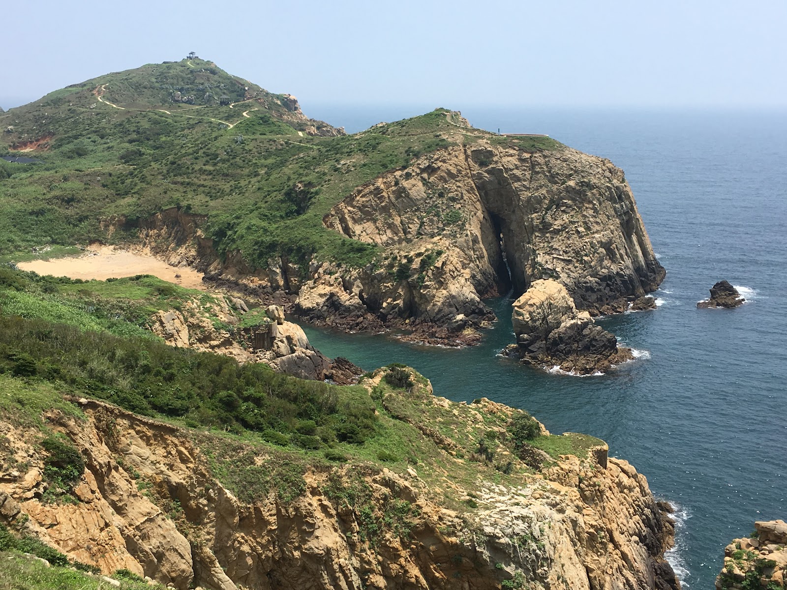 神祕小海灣空拍海灣岬角與海蝕洞穴全景,金黃沙灘與碧藍海水